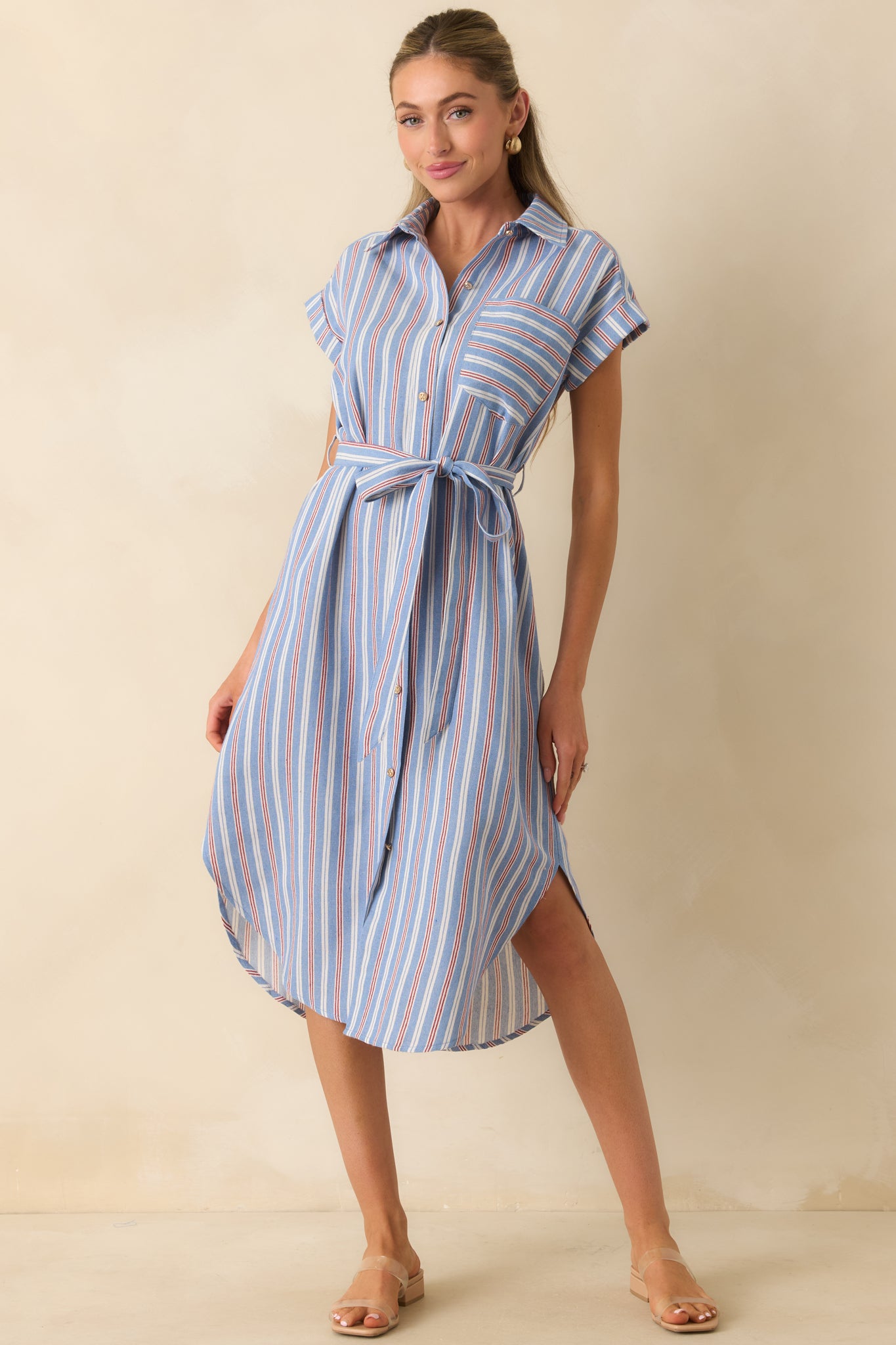 Blue, red, and ivory shirtdress showcasing a button-front silhouette, cap sleeves, side slits, and a curved hemline.