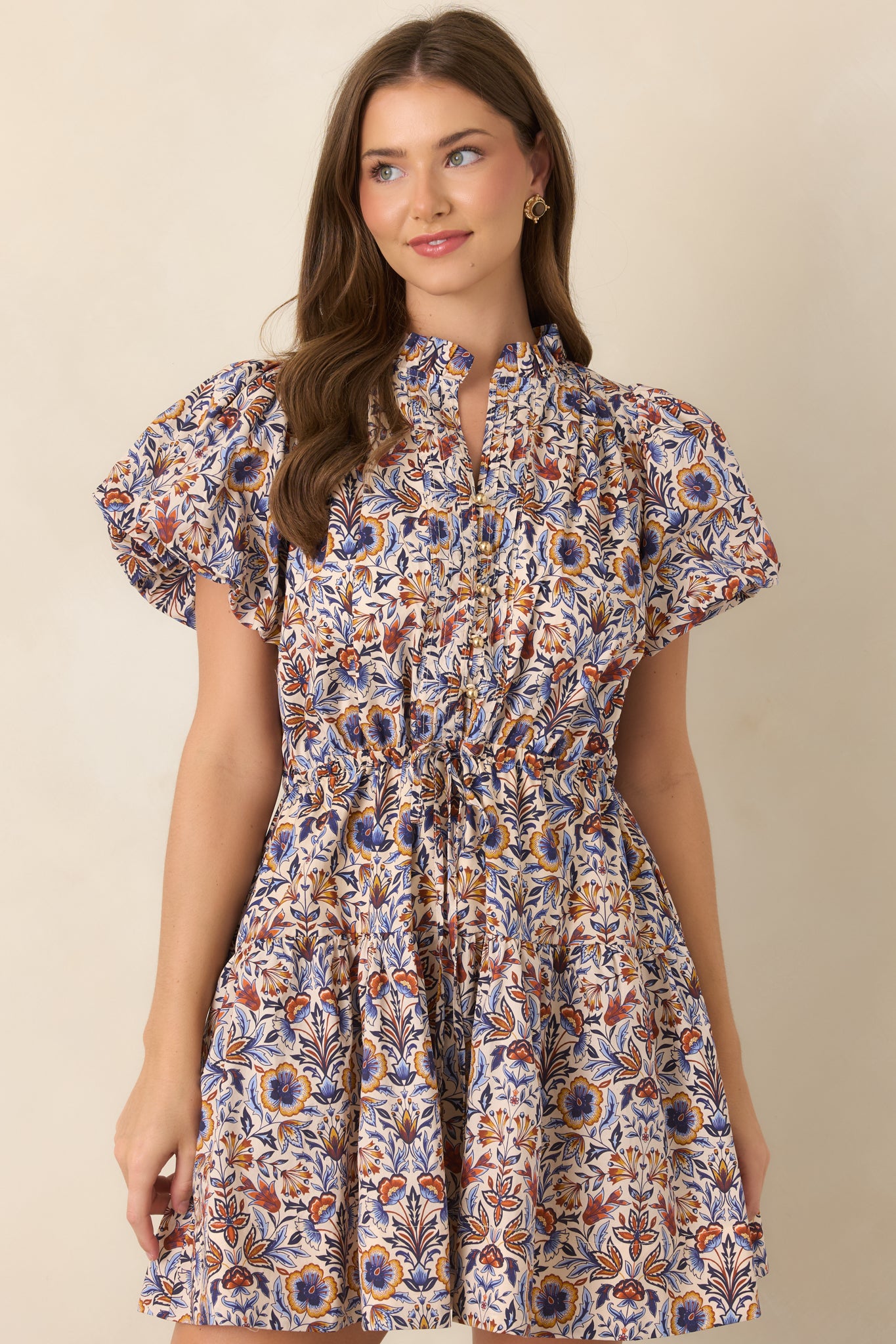 Detailed view of the blue, rust, and golden floral pattern against the ivory dress base