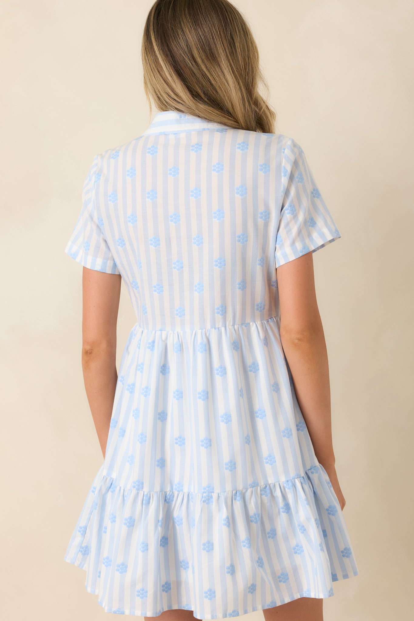 Blue stripe cotton mini dress showing the back of the tiered silhouette with embroidered floral detailing and relaxed fit.
