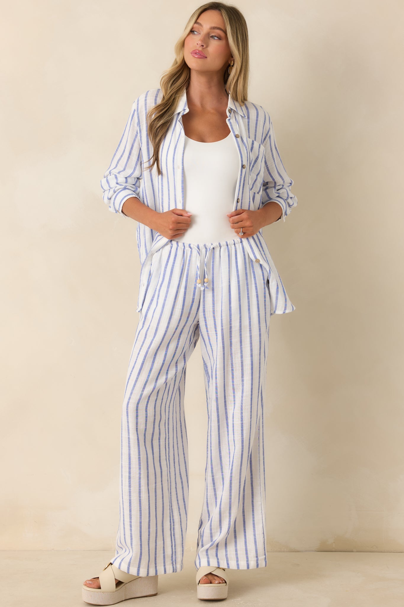 Blue striped button-up shirt featuring a collared neckline, functional front button closure, and relaxed gauzy cotton fit.