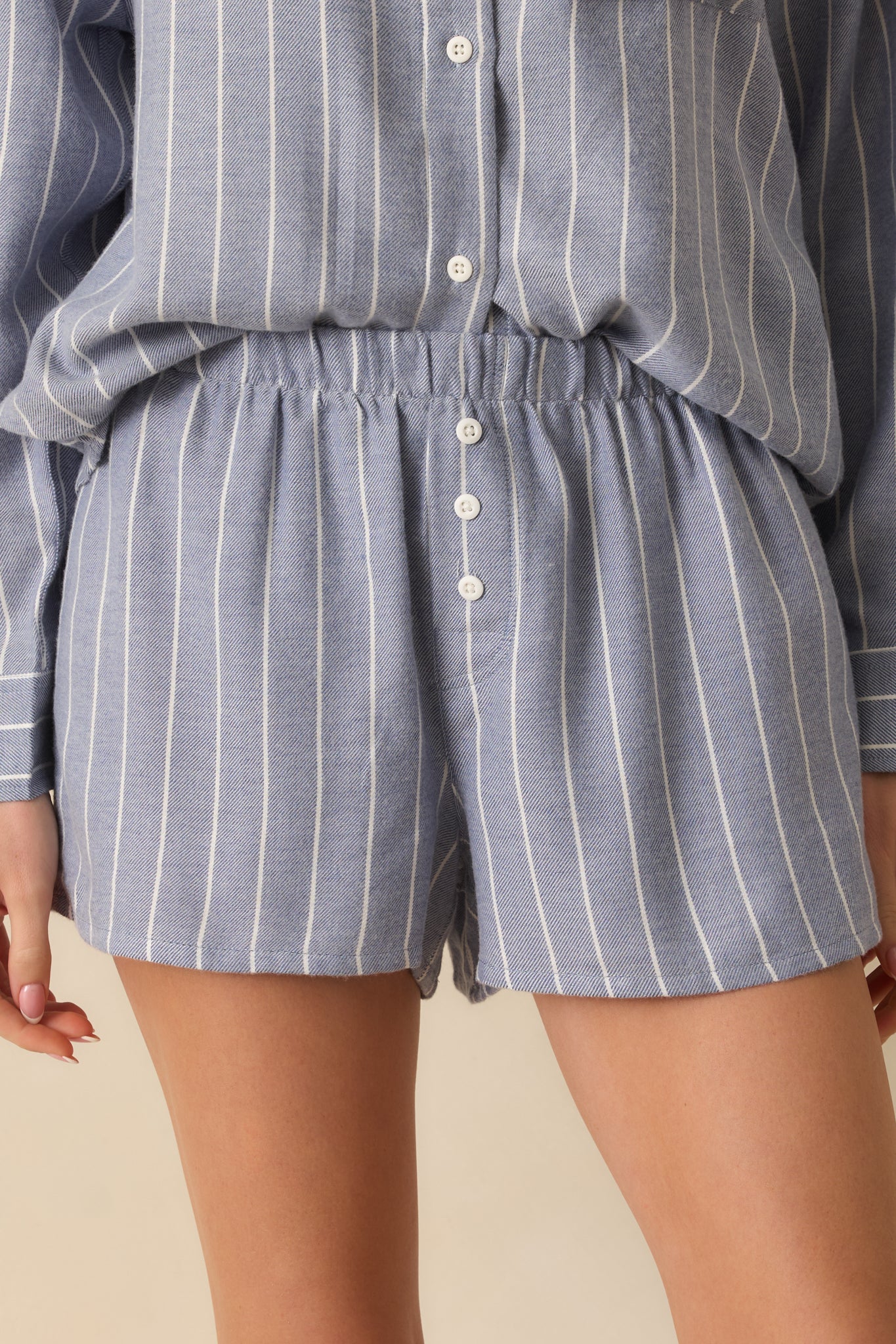 Tight view of blue striped knit fabric, elastic waistband, and button fly detail for texture focus.