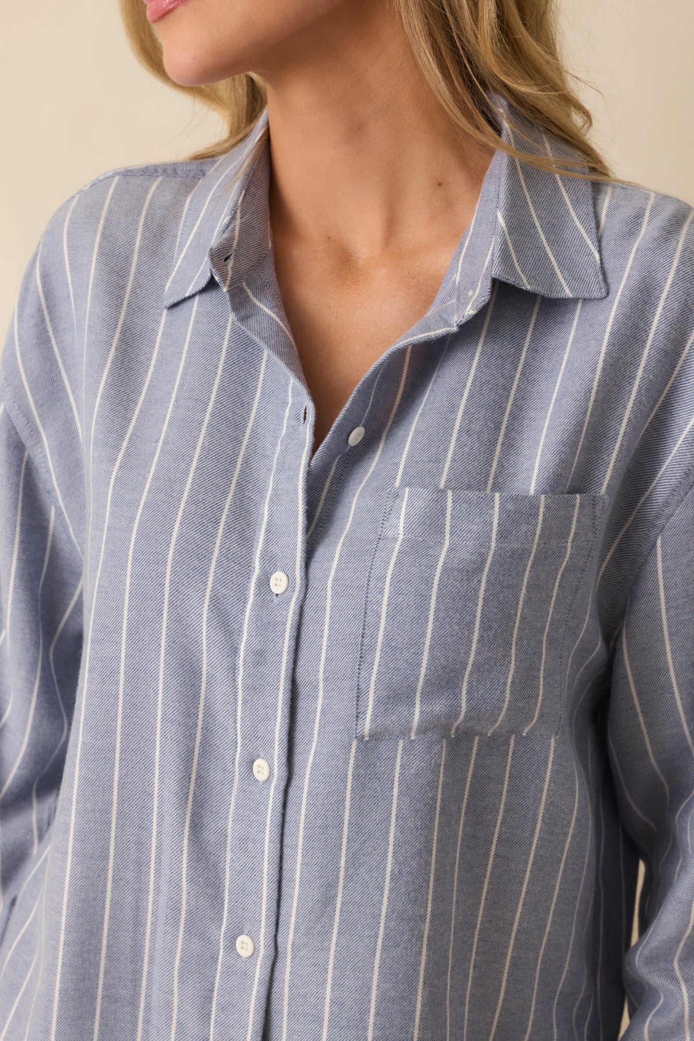 Close view of blue striped knit fabric, highlighting collar, buttons, and pocket detail.