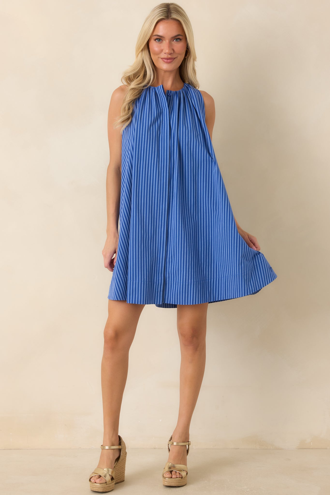 Electric blue striped mini dress featuring a gathered high neckline, sleeveless design, and relaxed swing silhouette.