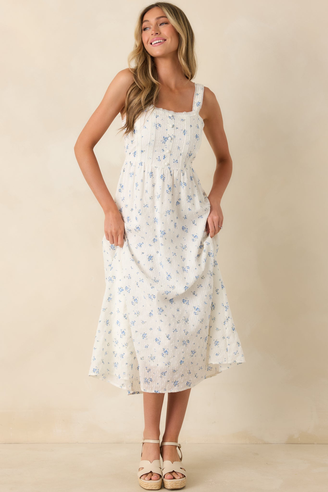 Blue floral cotton midi dress with Swiss dot detailing, vertical lace panels, crochet trim, and an effortless warm-weather silhouette.