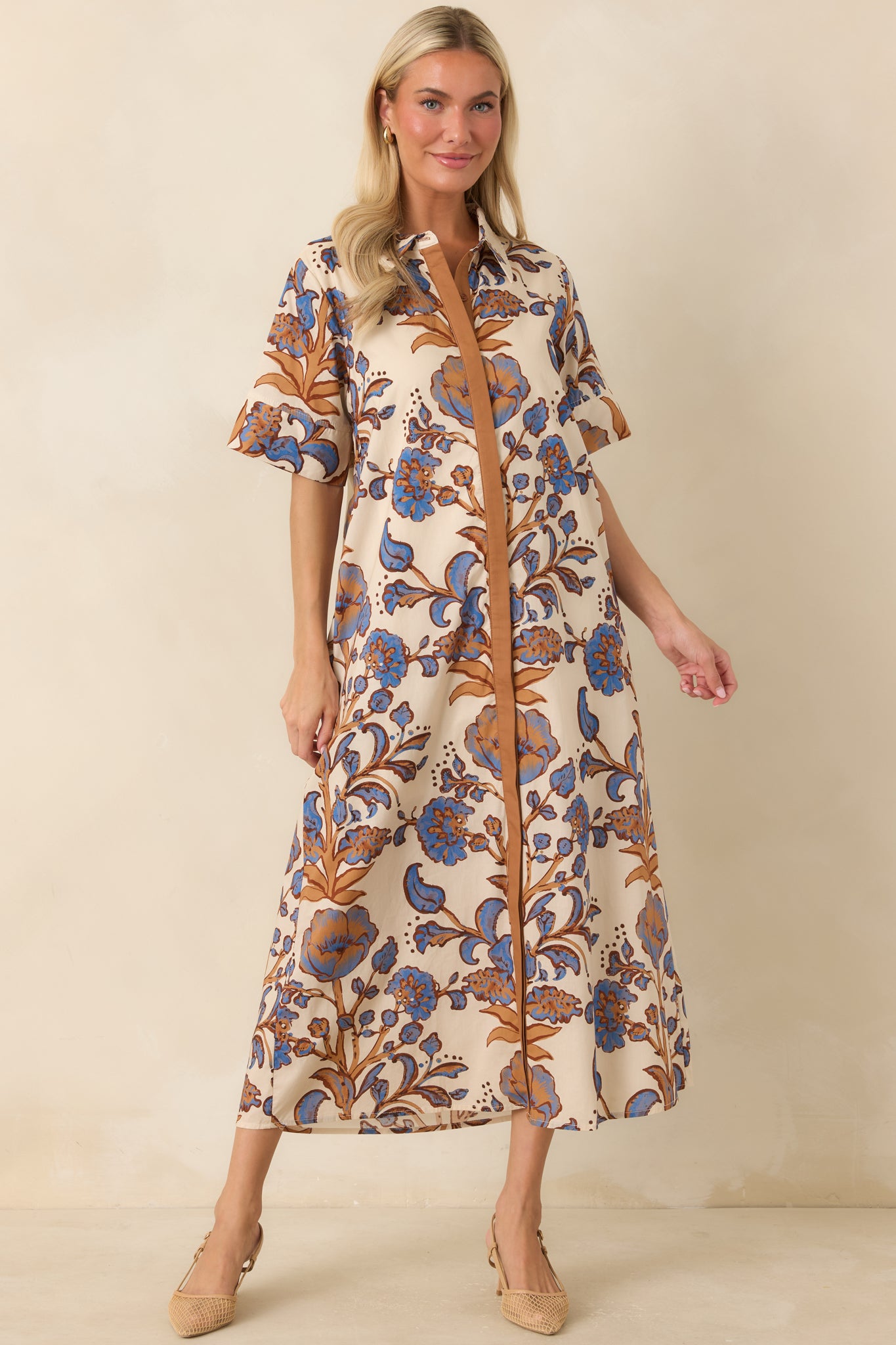 Floral shirt dress featuring a vivid blue, tan, and rust brown print, button-front placket, and relaxed cotton silhouette.