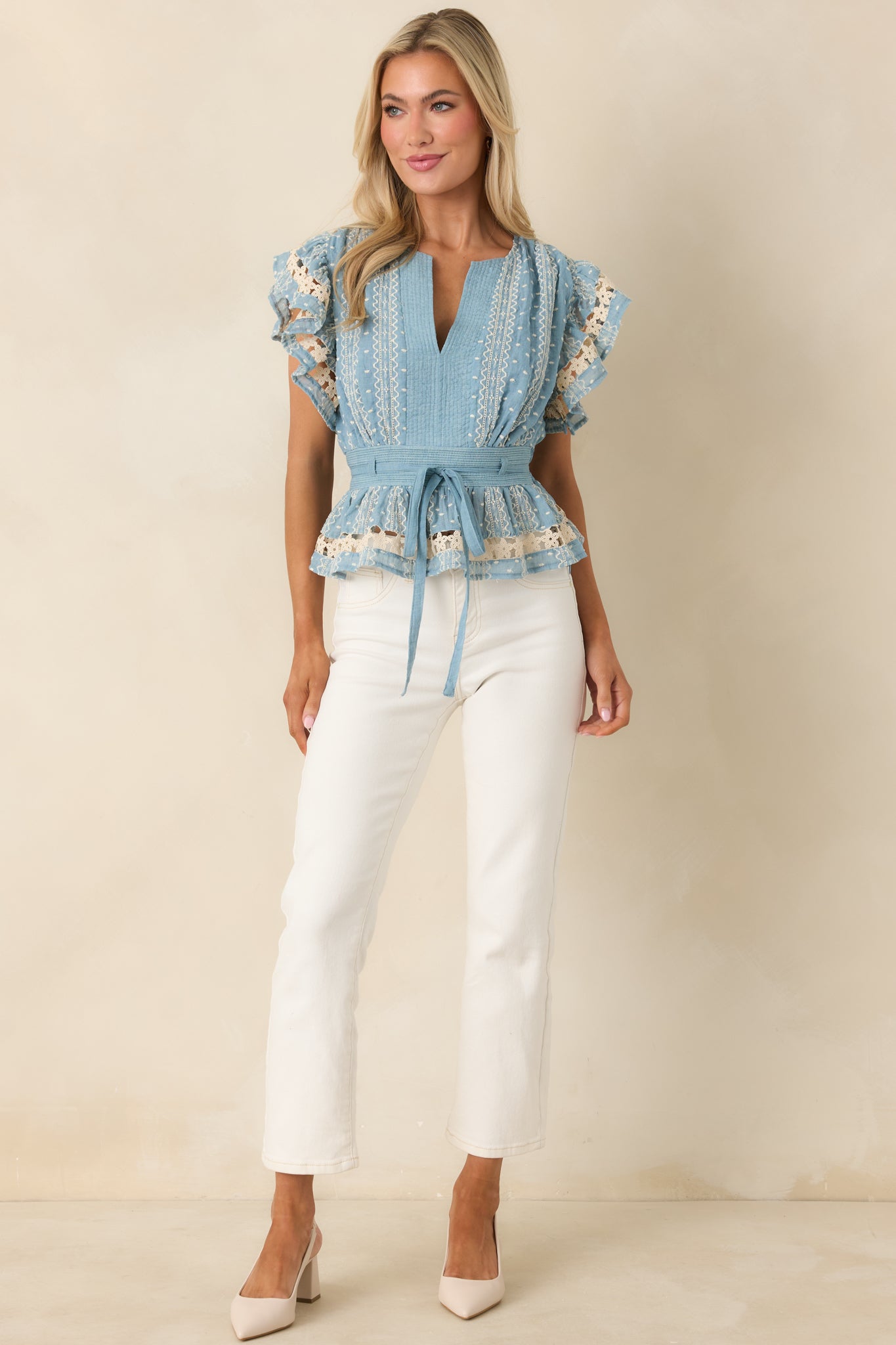 Blue top with flared peplum hem, V-neck design, and optional fabric belt accentuating the waist.