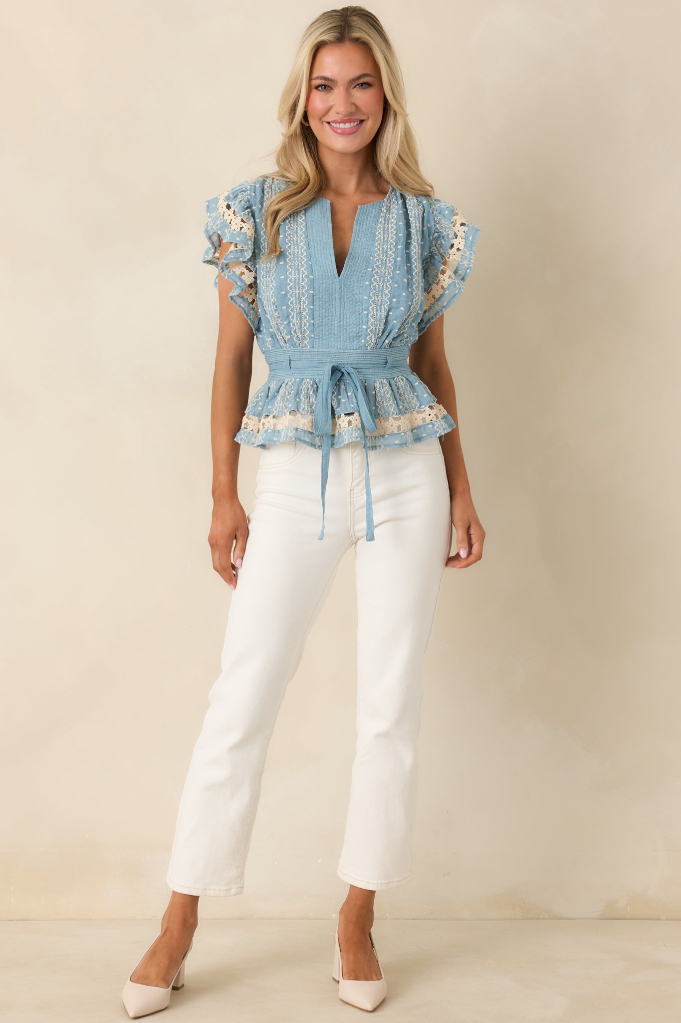 Blue top with structured peplum silhouette, embroidered lace trim, and elasticized rear waistband for shape.