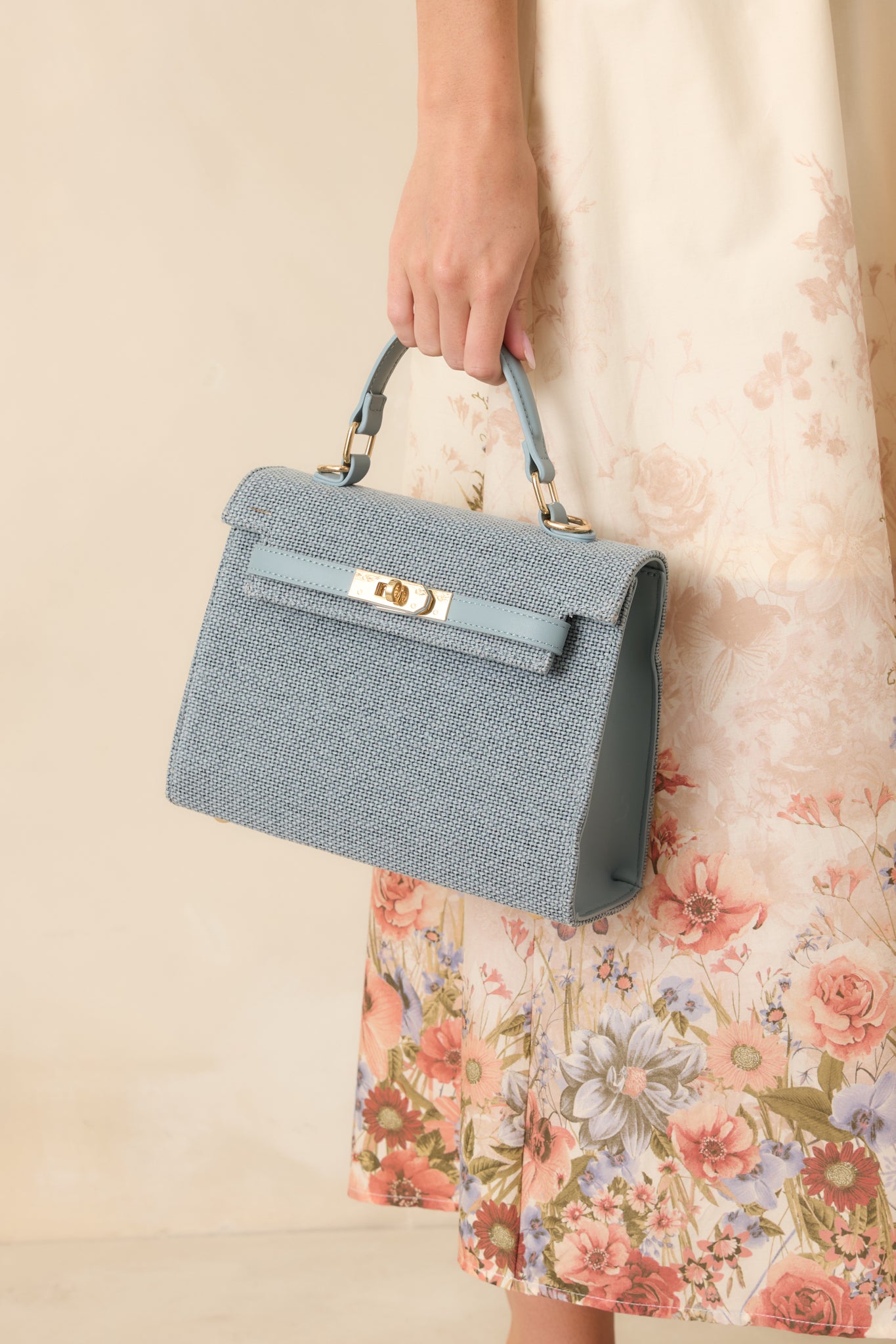 Light blue textured handbag showcasing a woven body, structured handle, fold-over design, and optional shoulder strap.