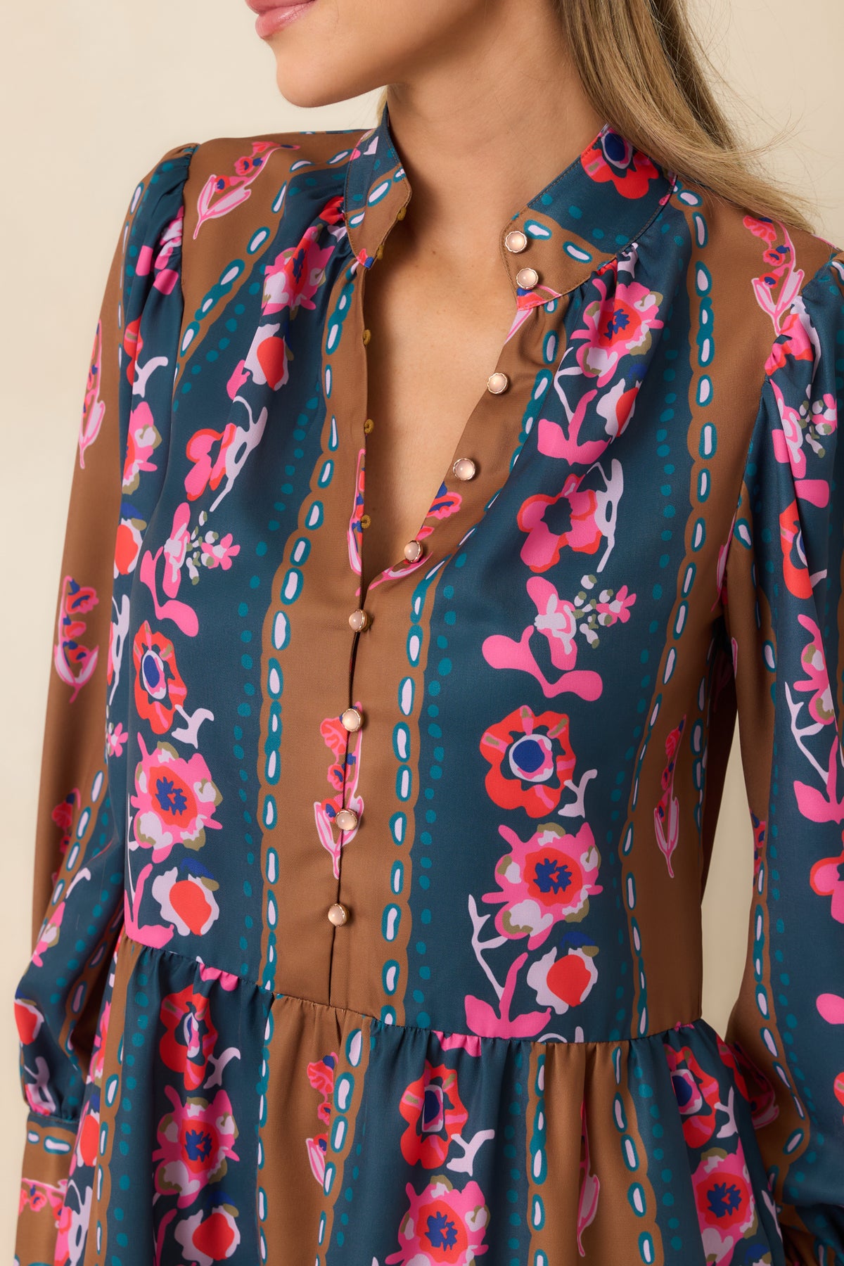 Delicate blush buttons, stand collar, and wide sleeve cuff showcase the detailed finishing of the floral striped dress.