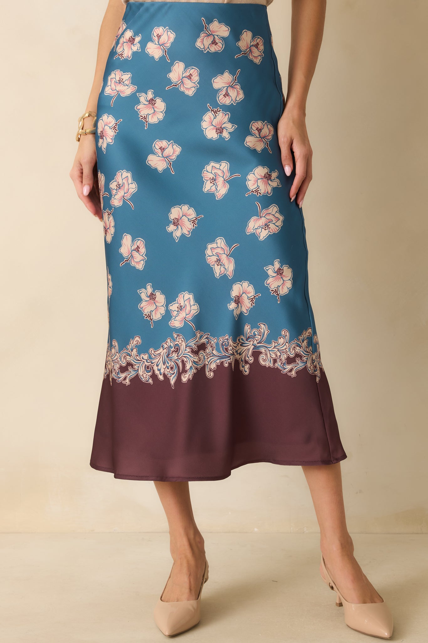 Zoomed-in view of the blush and ivory floral print against the blue satin fabric with visible sheen.