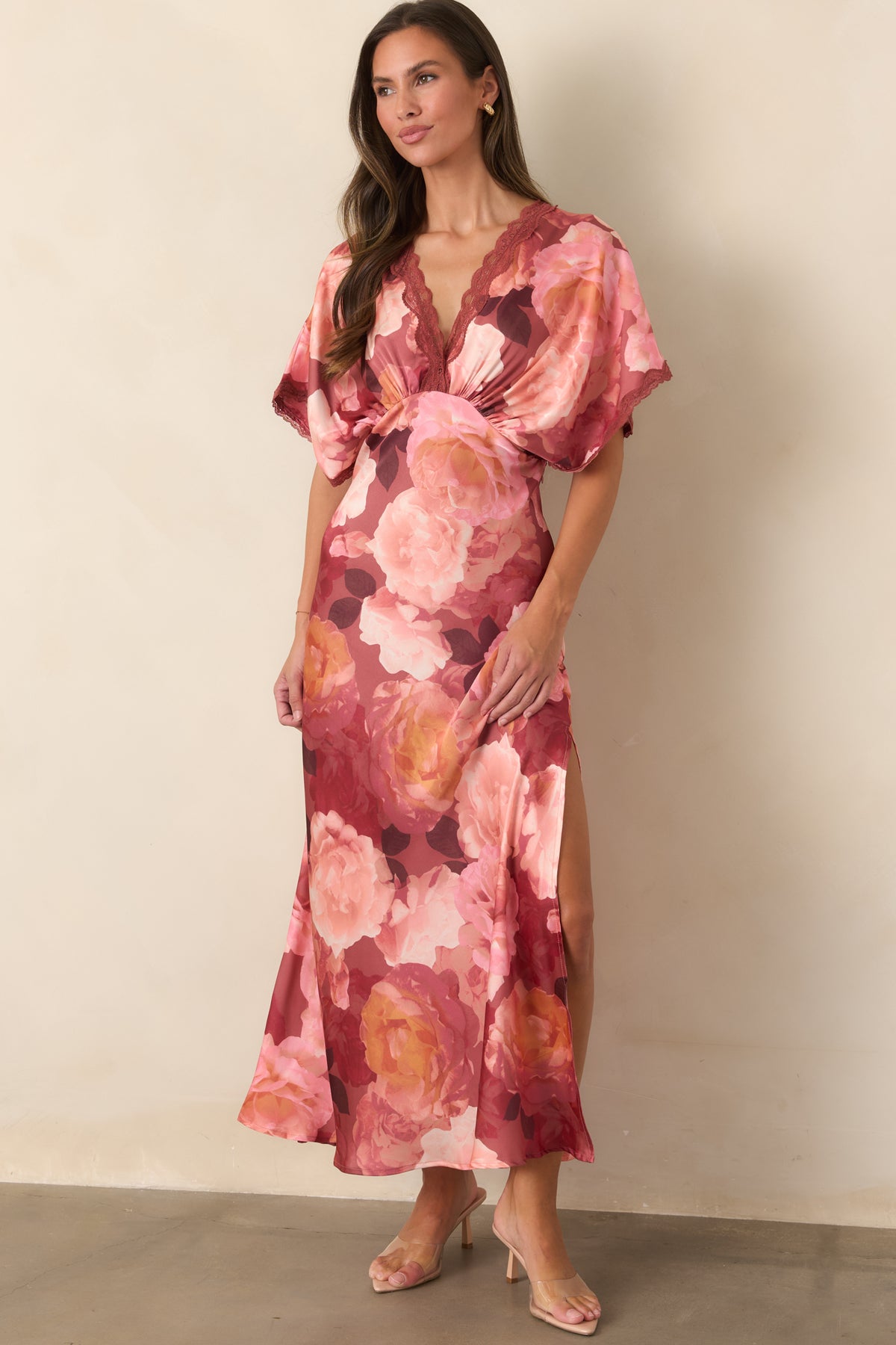 Floor-length satin dress covered in oversized blush, rose, and coral florals with a graceful defined waist.