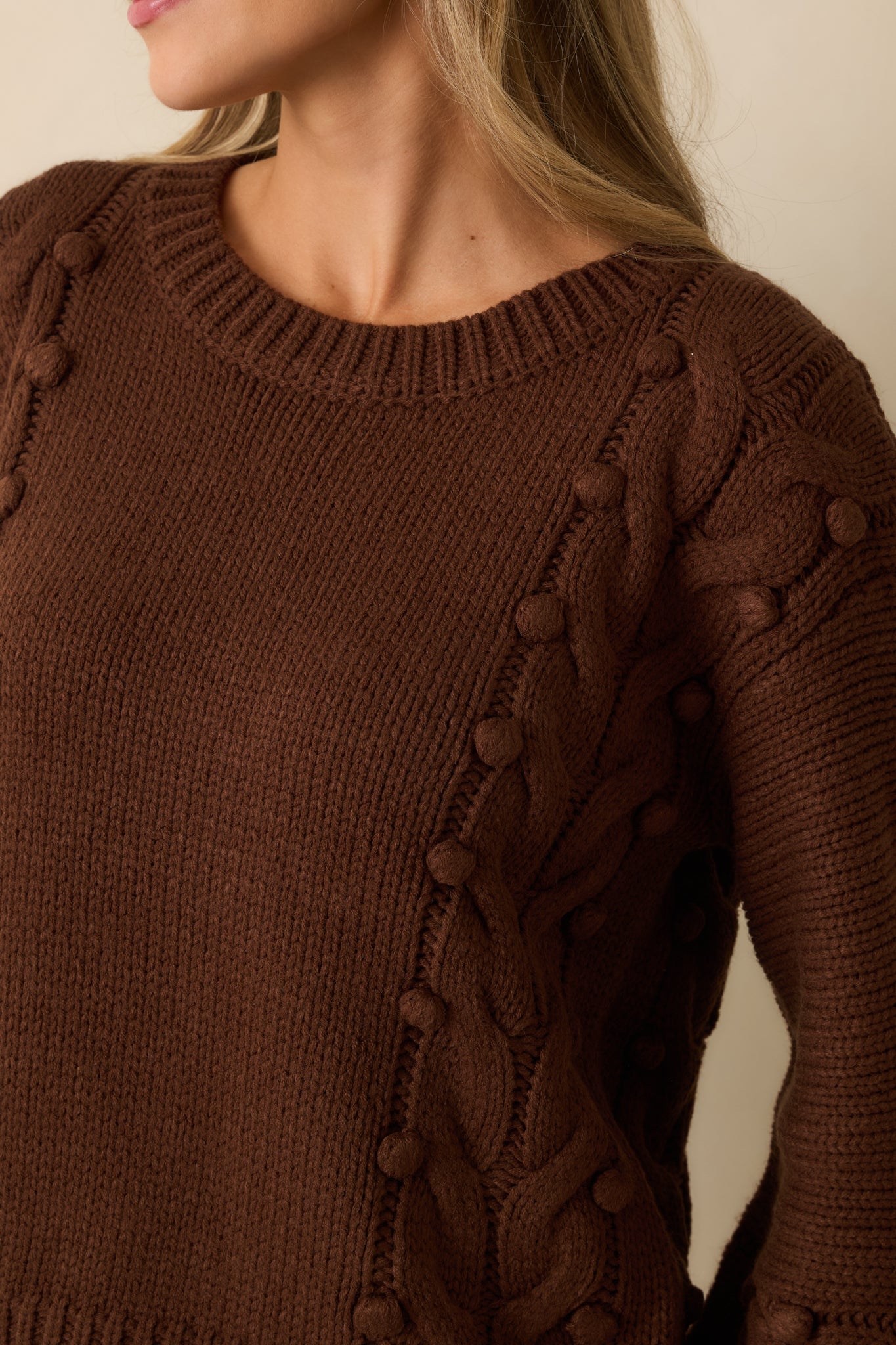 Detailed look at the bobble accents and cable knit texture in the chocolate brown sweater.