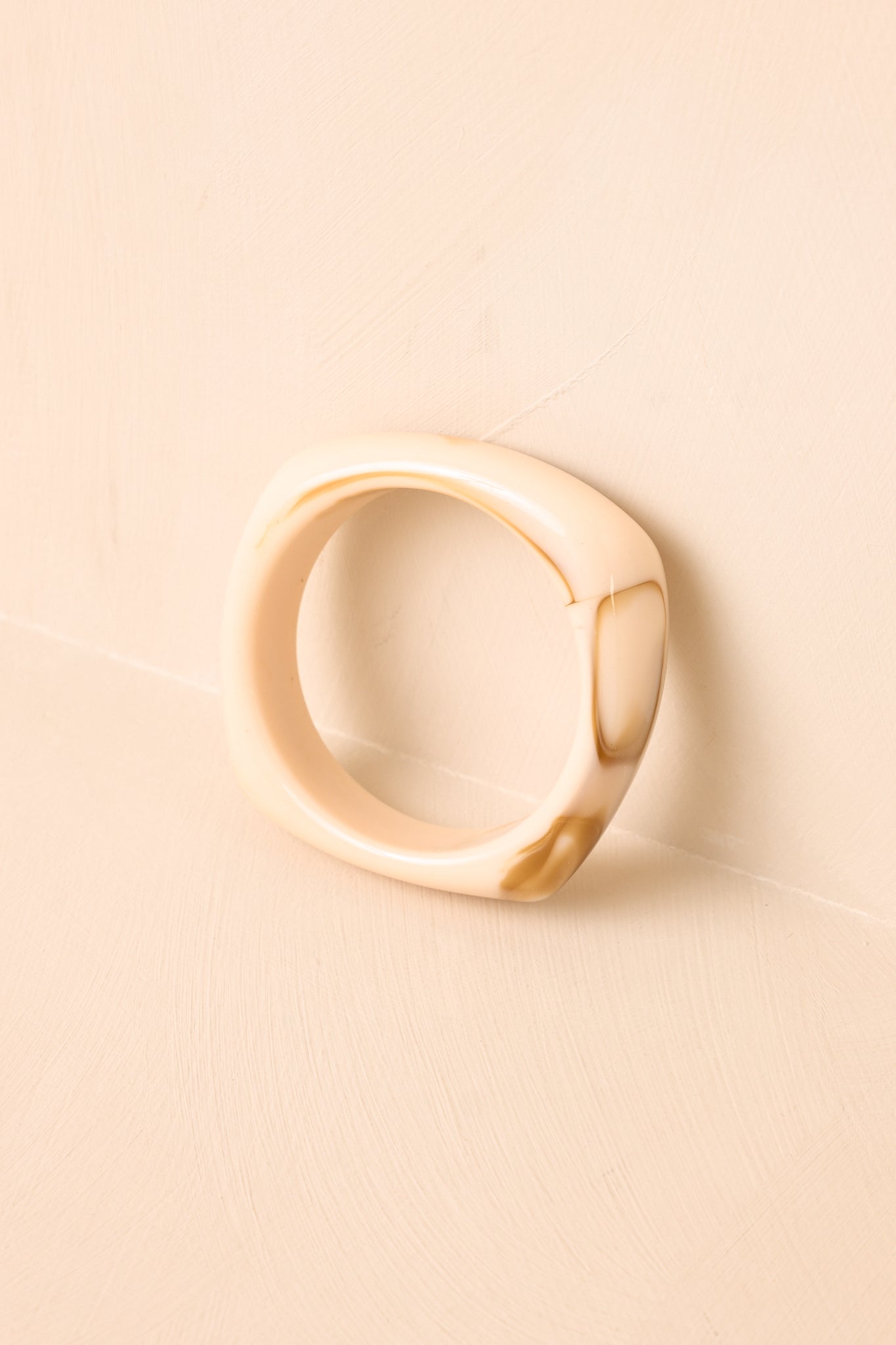 Bold bangle presented on a neutral backdrop, emphasizing the glossy resin construction and refined shape.