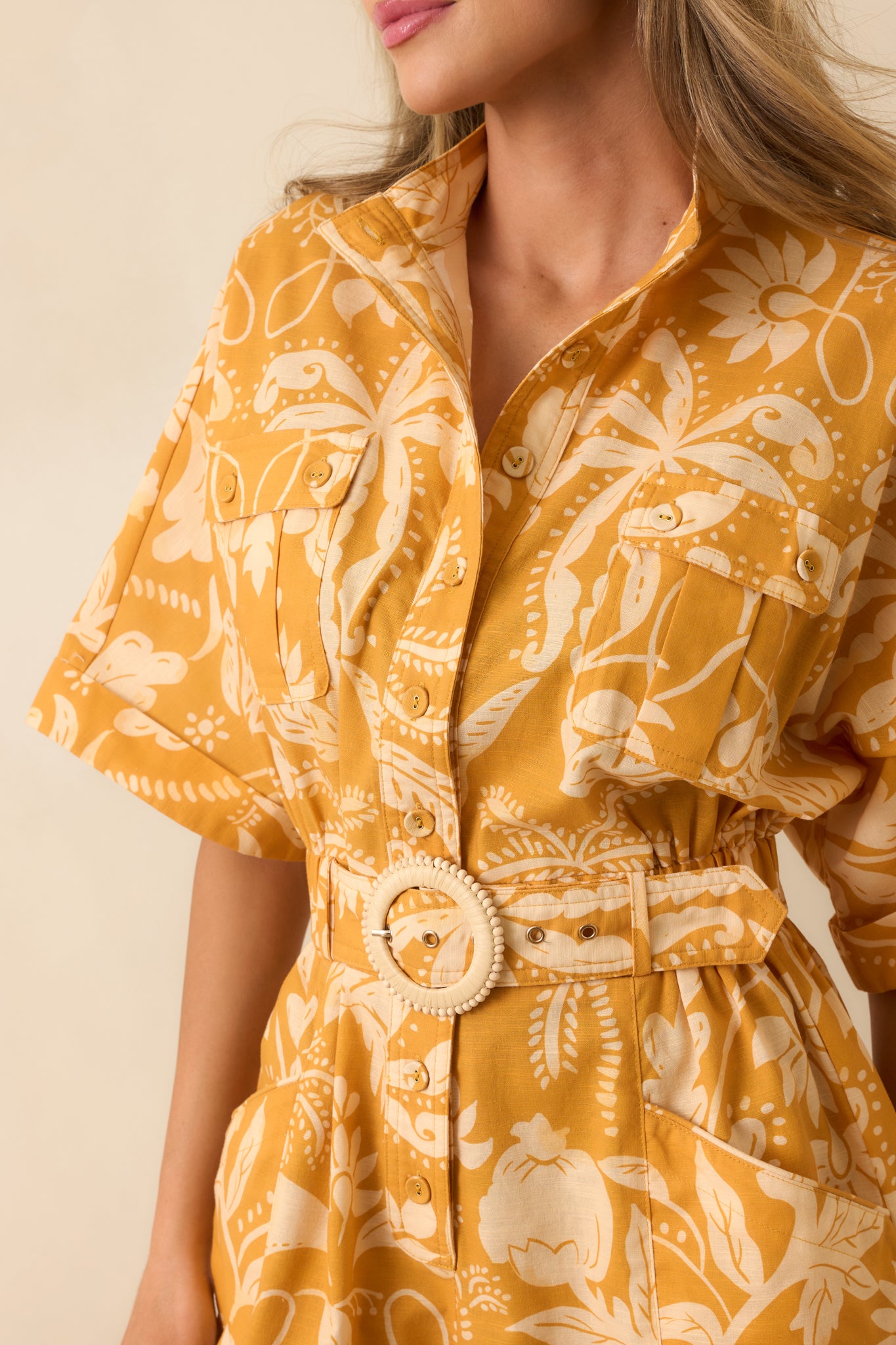 Close-up of the botanical damask fabric featuring intricate marigold and ivory patterning, button-front accents, and woven buckle detail.