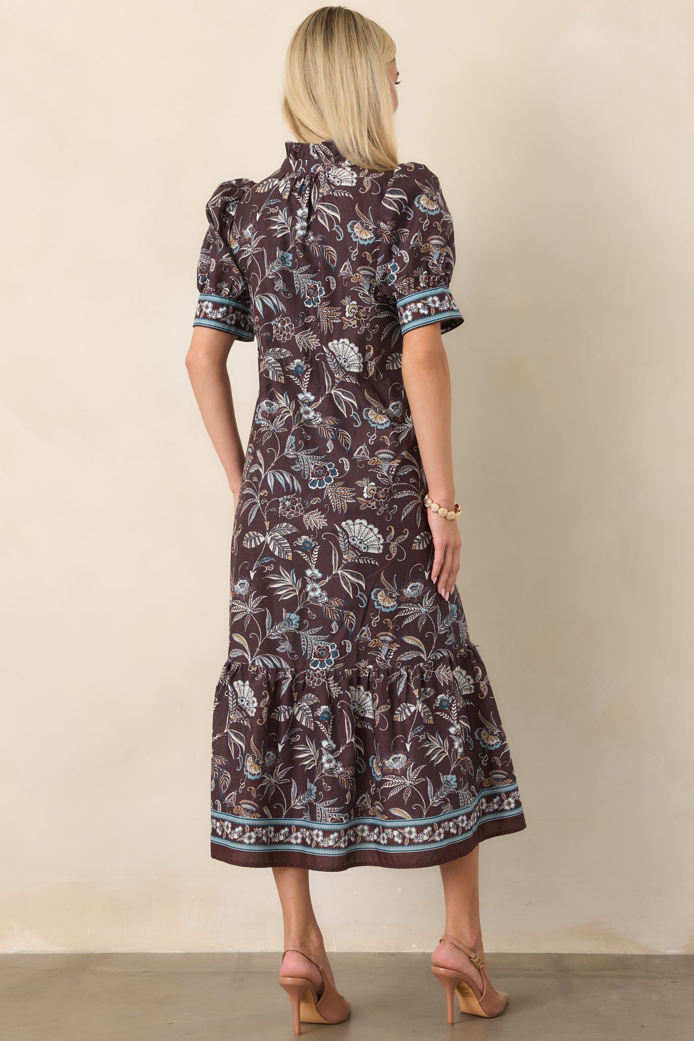 Rear view of the botanical midi dress showcasing its flowing silhouette, intricate floral print, short sleeves, and decorative hem border.