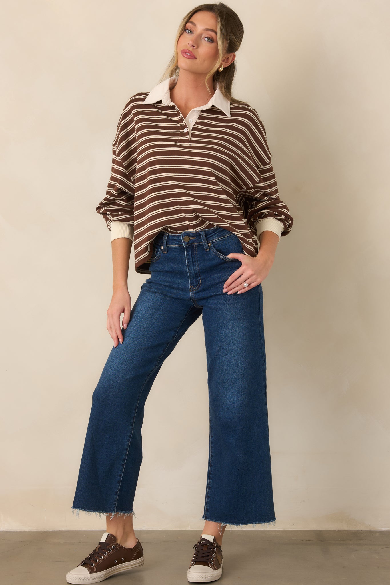 Loose boxy sweater showcasing an ivory striped pattern, partial button placket, contrasting collar, and coordinating cuffs.
