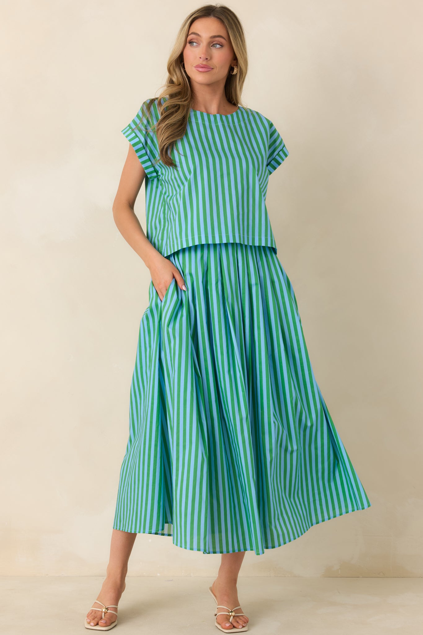 Boxy cotton top with vertical blue and green stripes, short cuffed sleeves, and a structured round neckline.