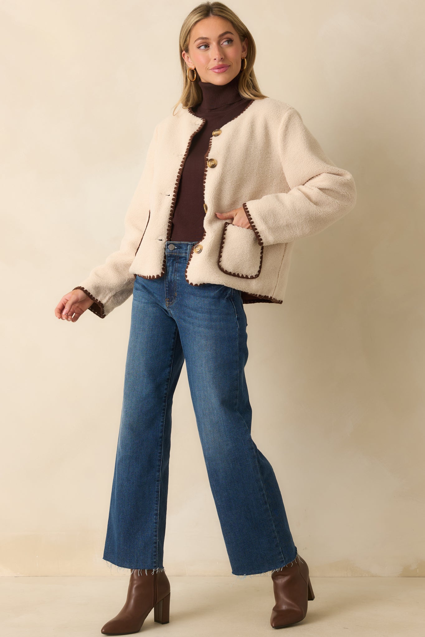 Boxy ivory sherpa jacket with functional button closure, whipstitch detailing, and a relaxed silhouette.