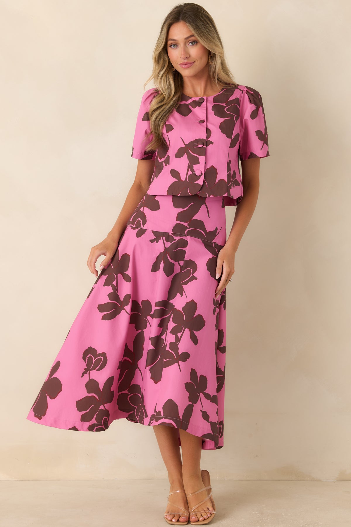Feminine floral top showcasing a vivid pink background, large chocolate brown blooms, softly structured shape, and button-front closure.