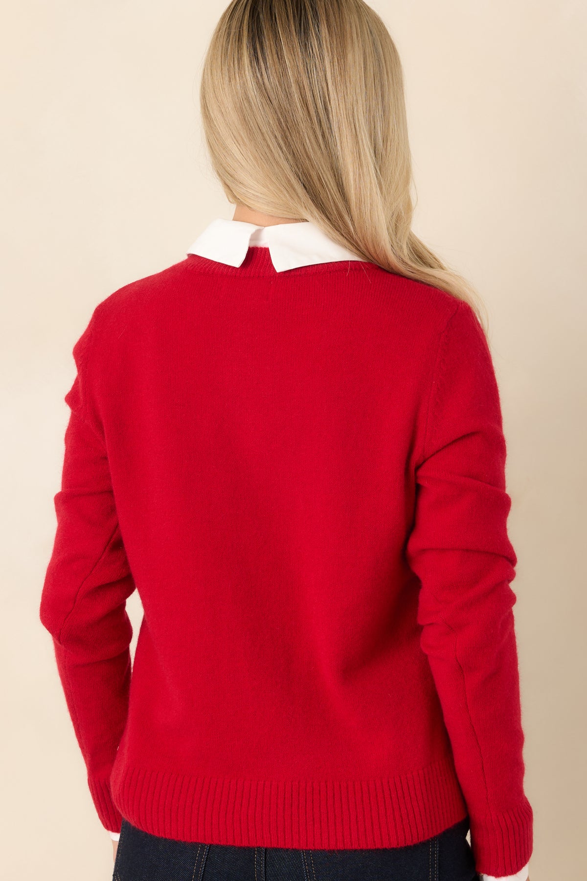 Rear view of the bright red knit top showing the crew neckline, long sleeves, and ribbed hem.