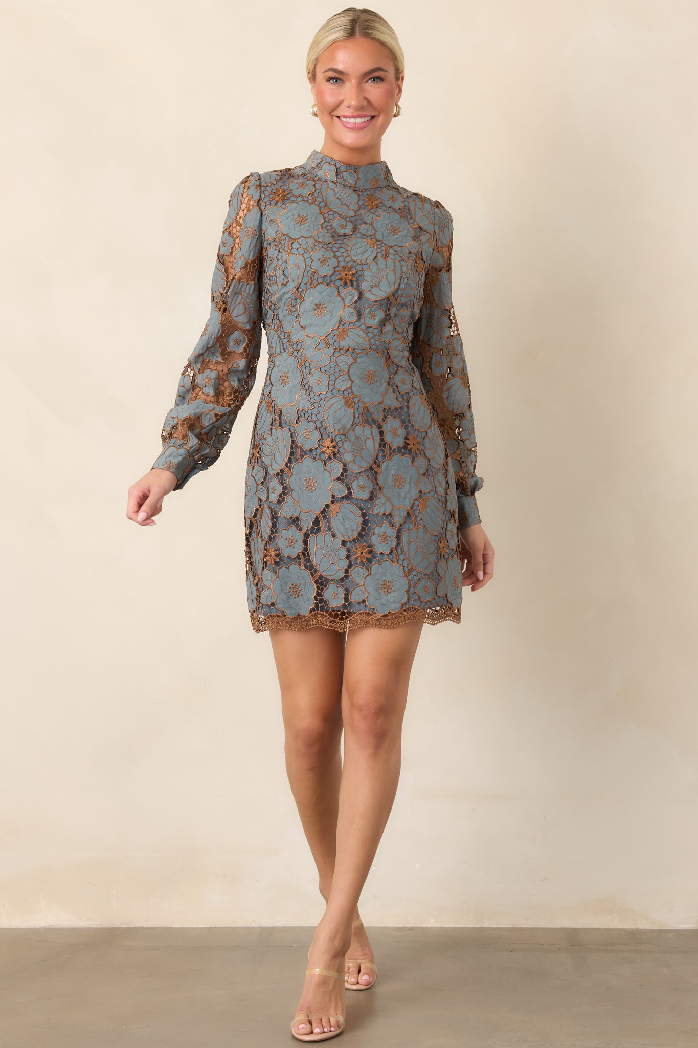 Mini dress featuring an intricate floral lace overlay with bronze-toned botanical detailing, long sleeves, and a high neckline.