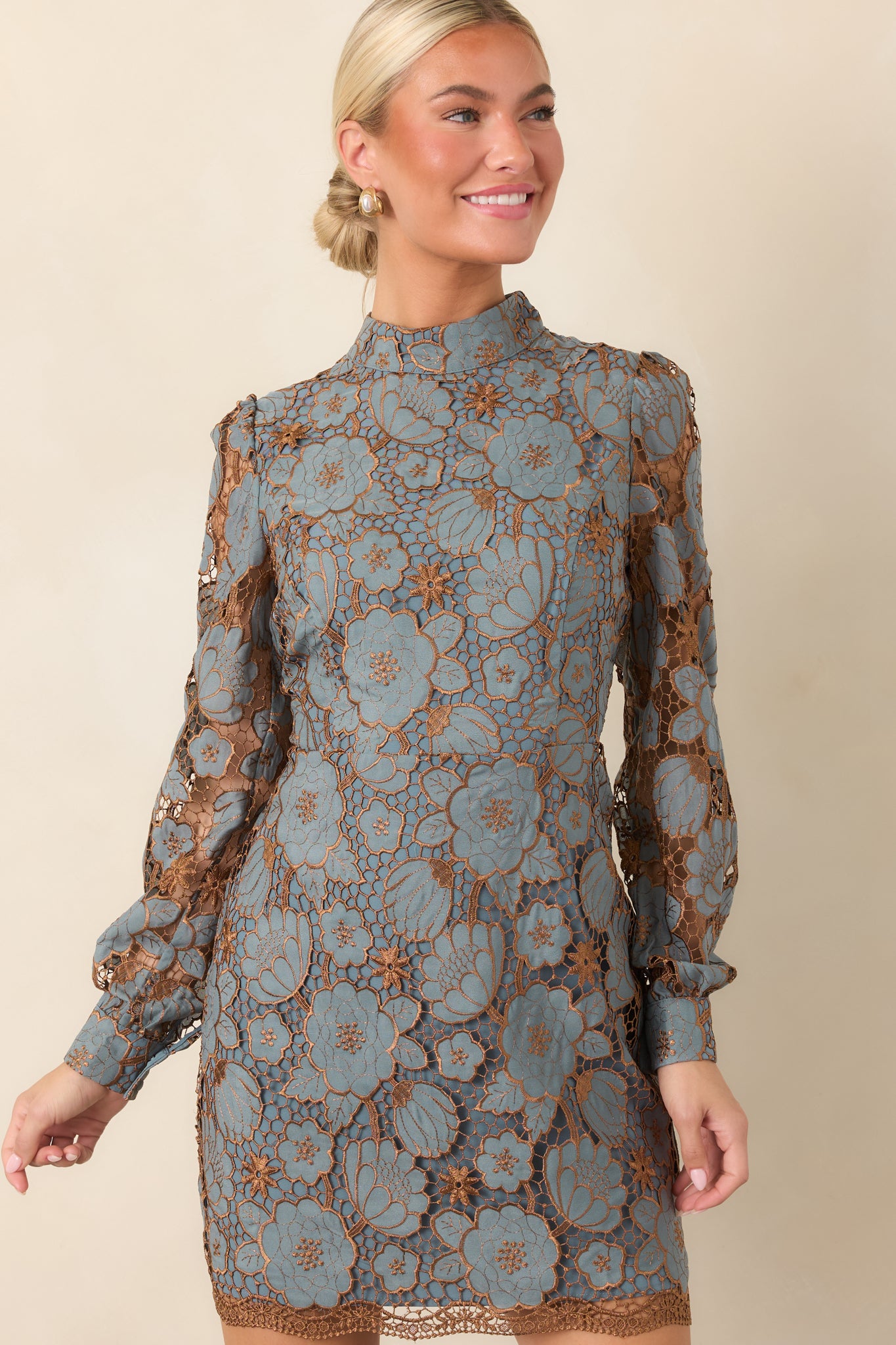 Mini dress detail showcasing the intricate lace flowers, fine bronze-toned embellishments, and high neckline.
