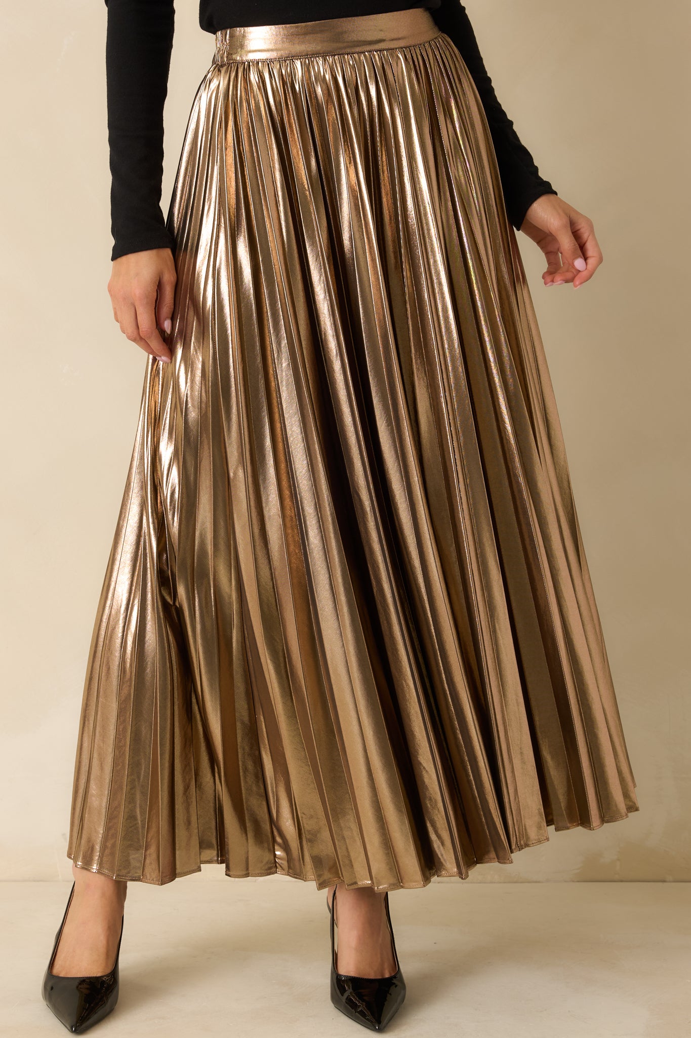Close view of the bronze maxi skirt’s high-rise front waistband and metallic pleated fabric.