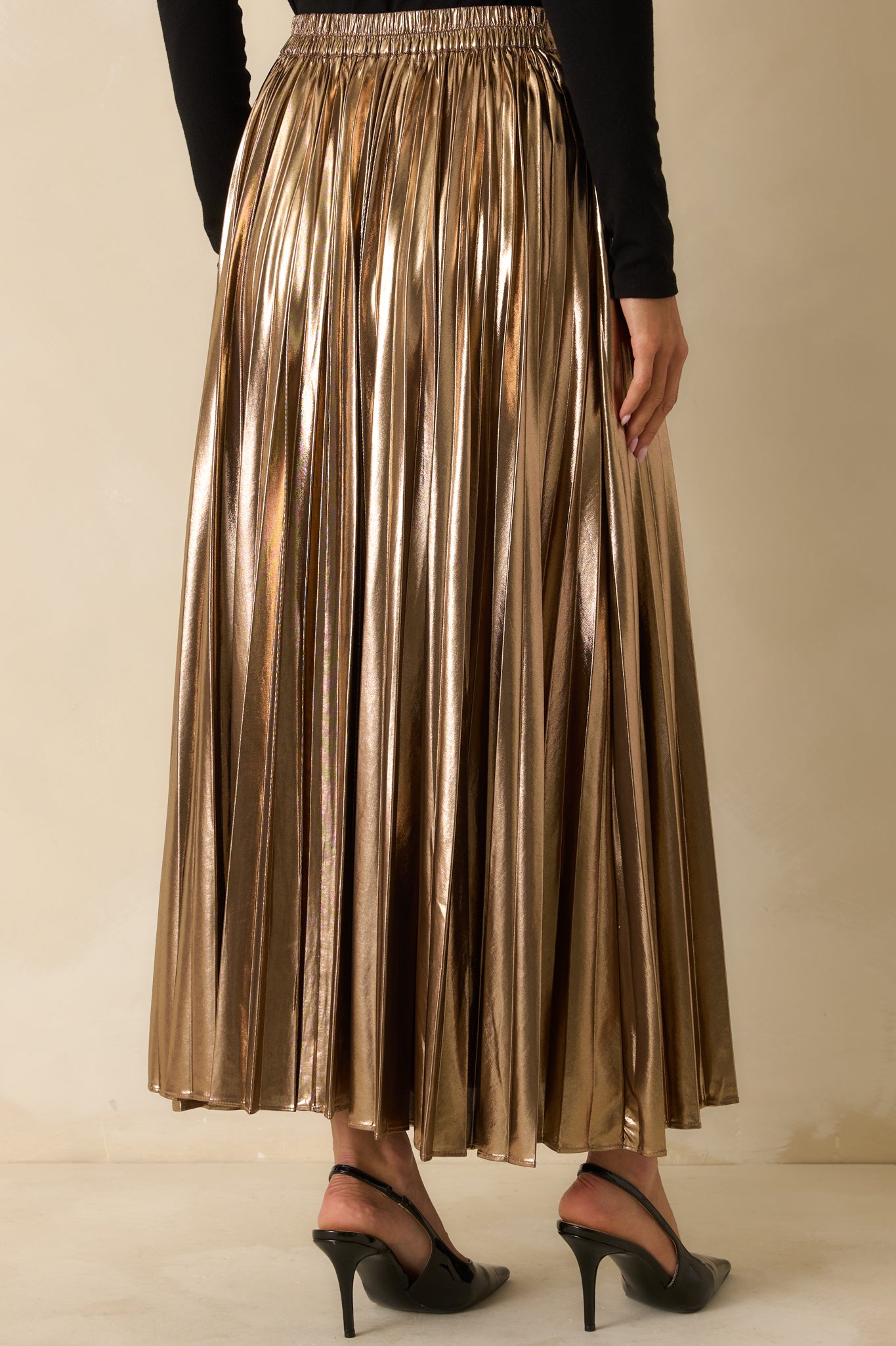 Rear view of the bronze metallic pleated maxi skirt highlighting the elastic back waistband and full pleated silhouette.