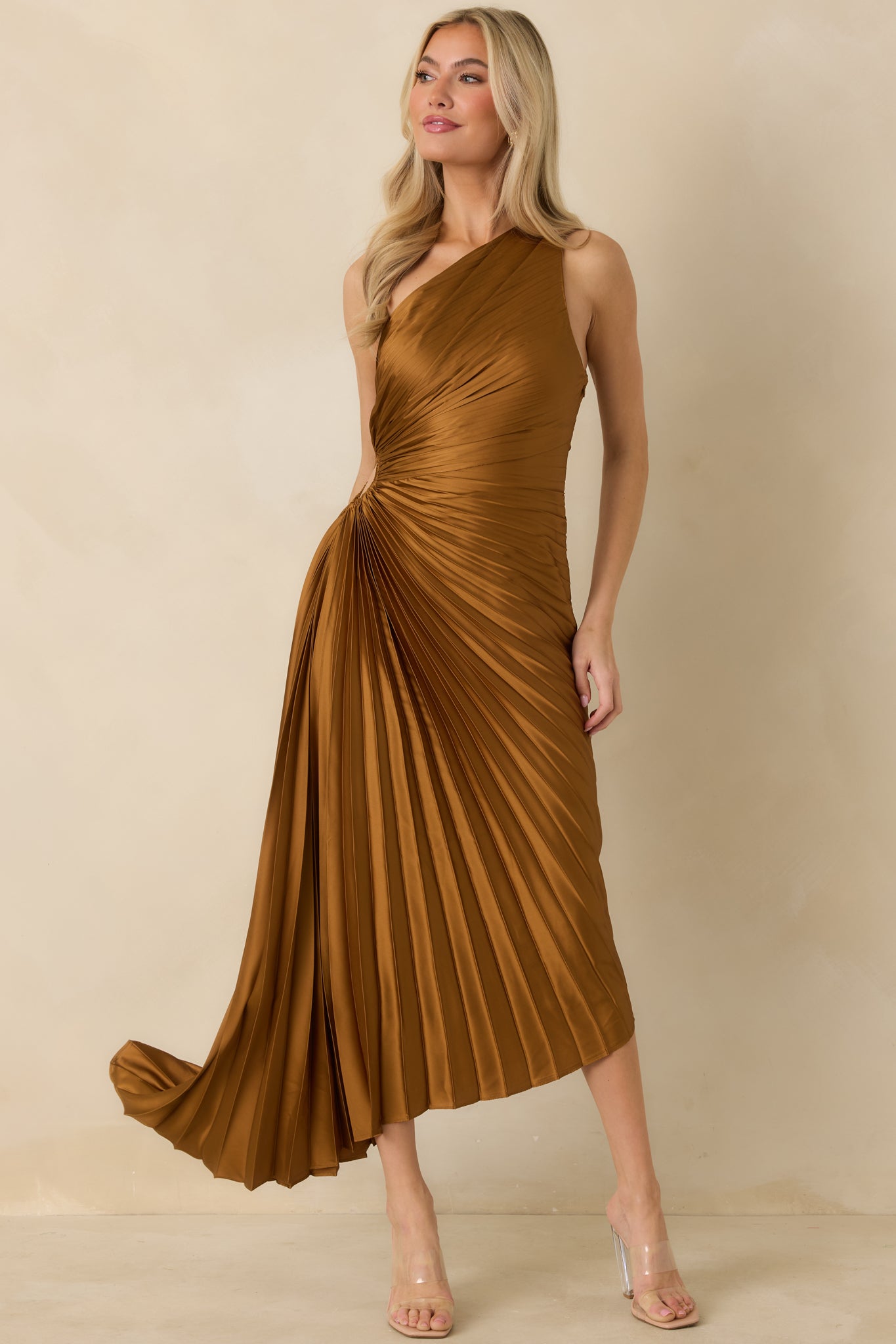 Full-length front view of bronze one-shoulder dress with allover pleats and flowing silhouette.