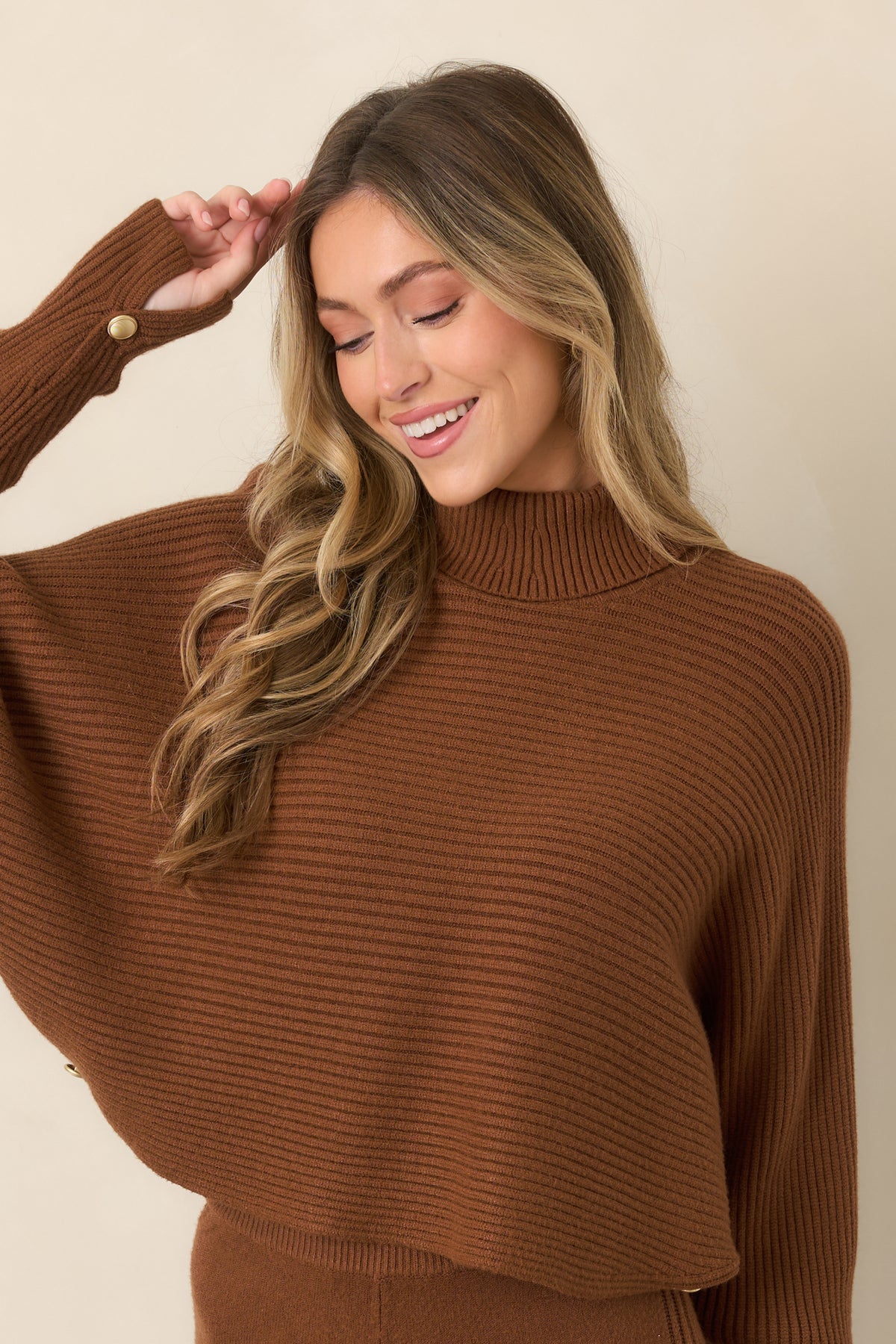 Detailed view of the sweater cuff featuring button accents, ribbed knit texture, and the relaxed width of the batwing sleeve.