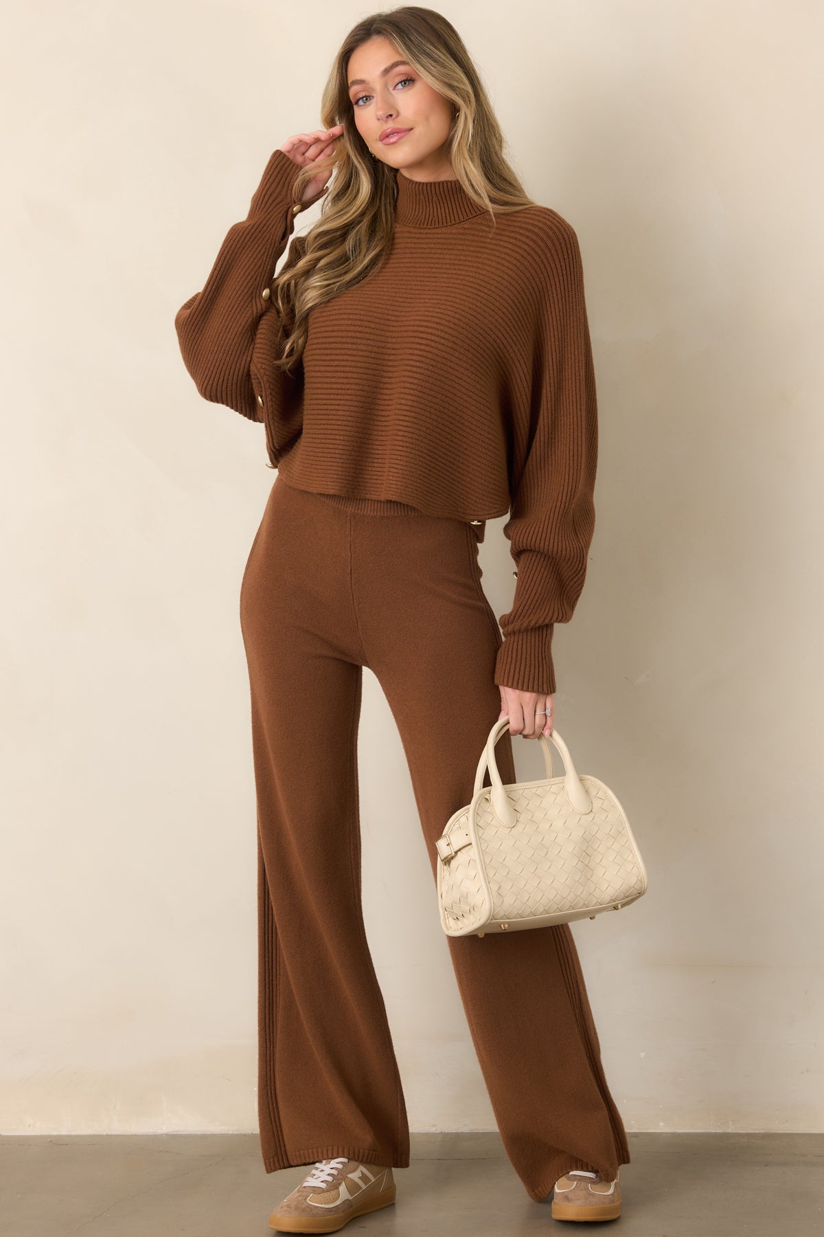 Rich brown pullover sweater designed with flowing batwing sleeves, a fitted turtleneck, ribbed construction, and a short cropped hem.