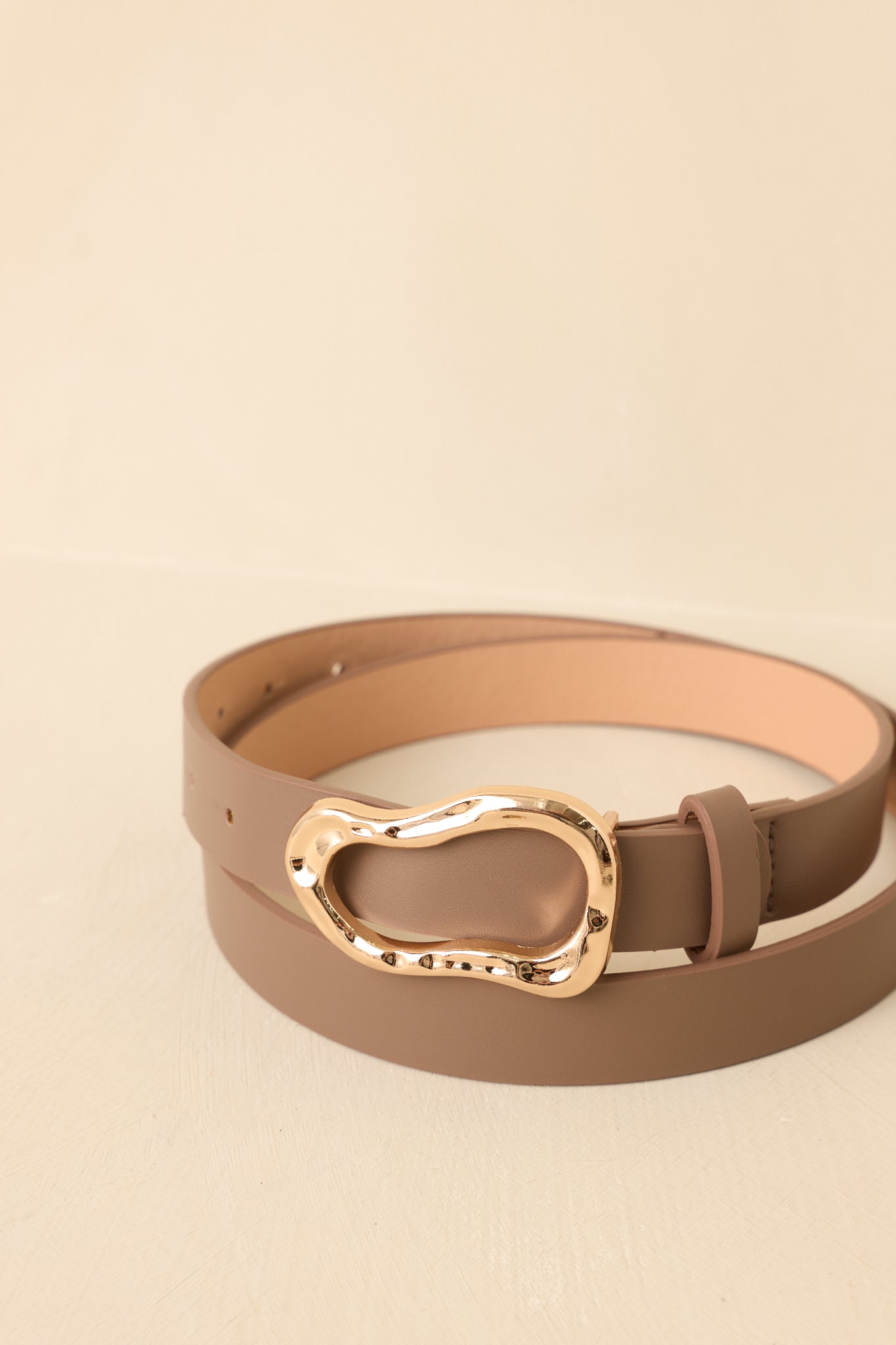 Brown belt with a gold buckle on a beige background