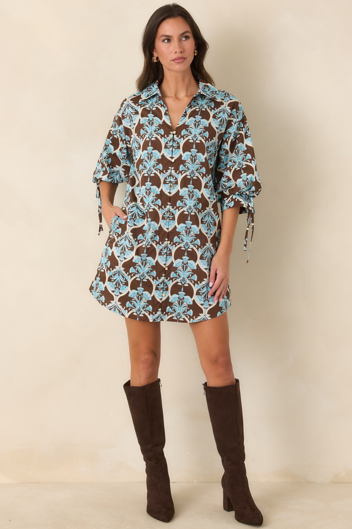 Brown floral mini dress with light blue motifs, ivory scrollwork, a pointed collar, and gold-tone front buttons.