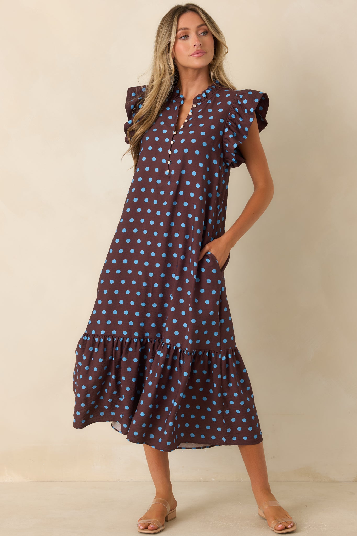 Brown and blue dotted dress showcasing pearl-inspired buttons, soft ruffle accents, and a flowing tiered skirt.