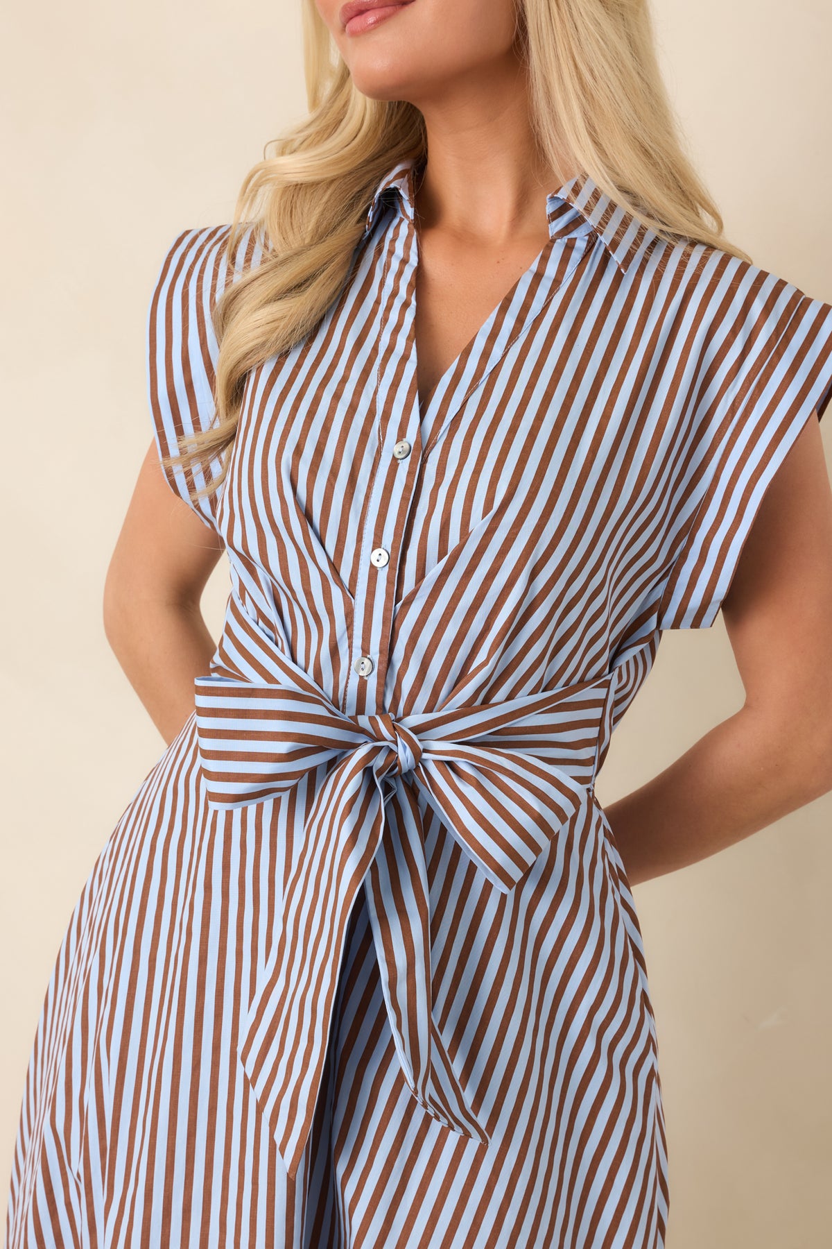 Close-up of the striped dress showing the collared neckline, partial button-front placket, and attached waist ties.