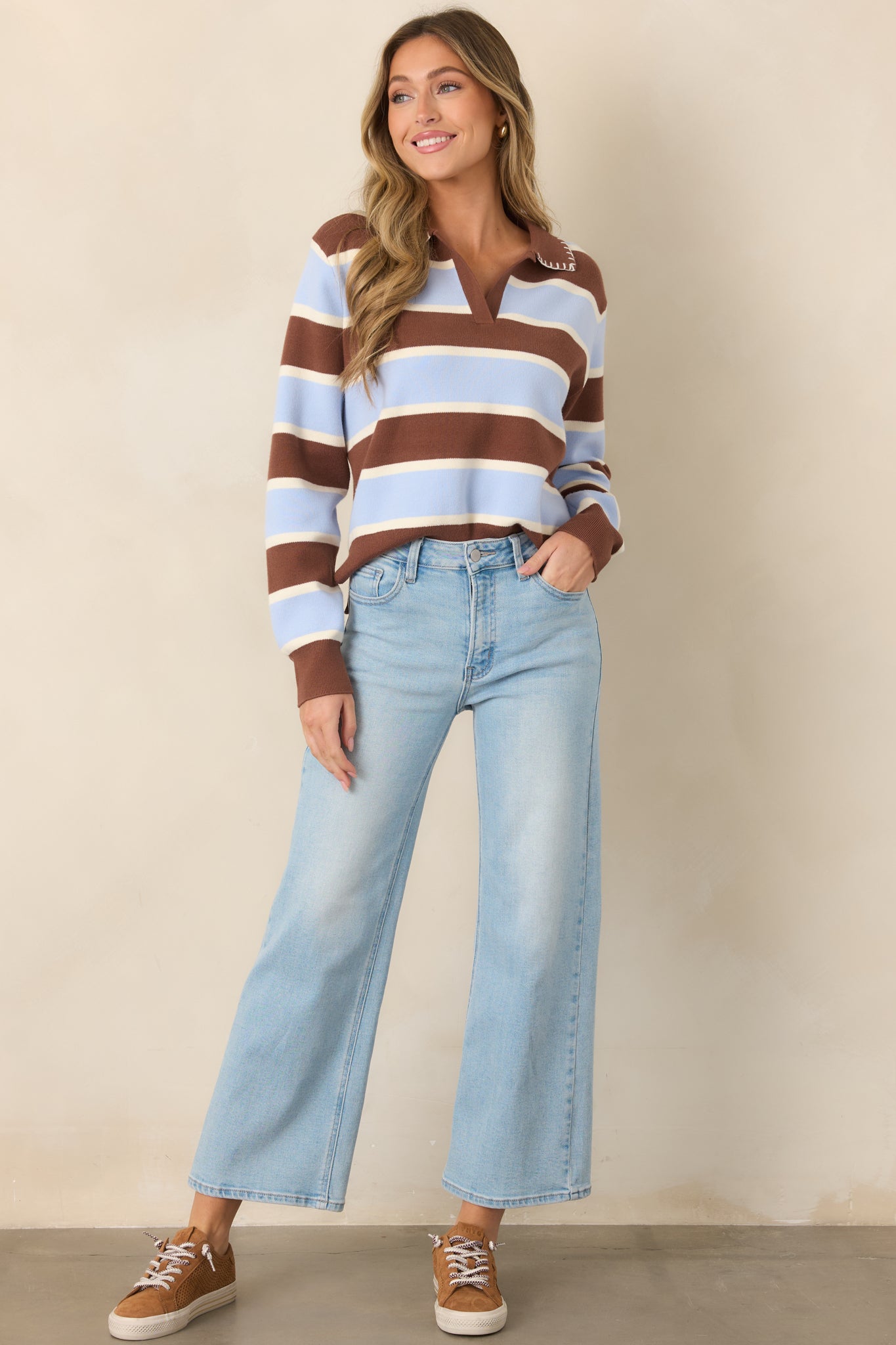 Relaxed color-blocked sweater with bold brown, blue, and white stripes, a pointed brown collar, V-shaped neckline, and full-length sleeves with ribbed cuffs.