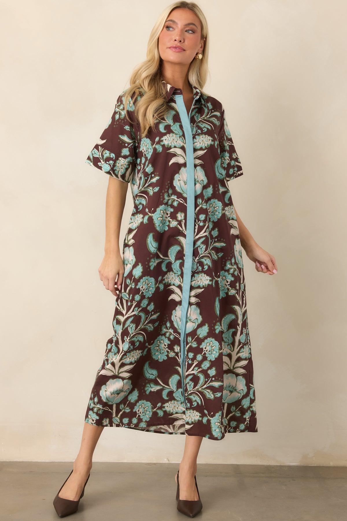 Aqua contrast detailing accents the front of the relaxed brown botanical dress, complementing its pointed collar and short sleeves.