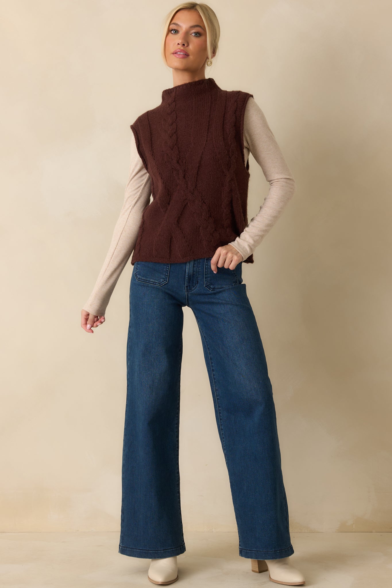 Brown cable knit sweater vest with a relaxed fit and mock neckline, styled for layering.