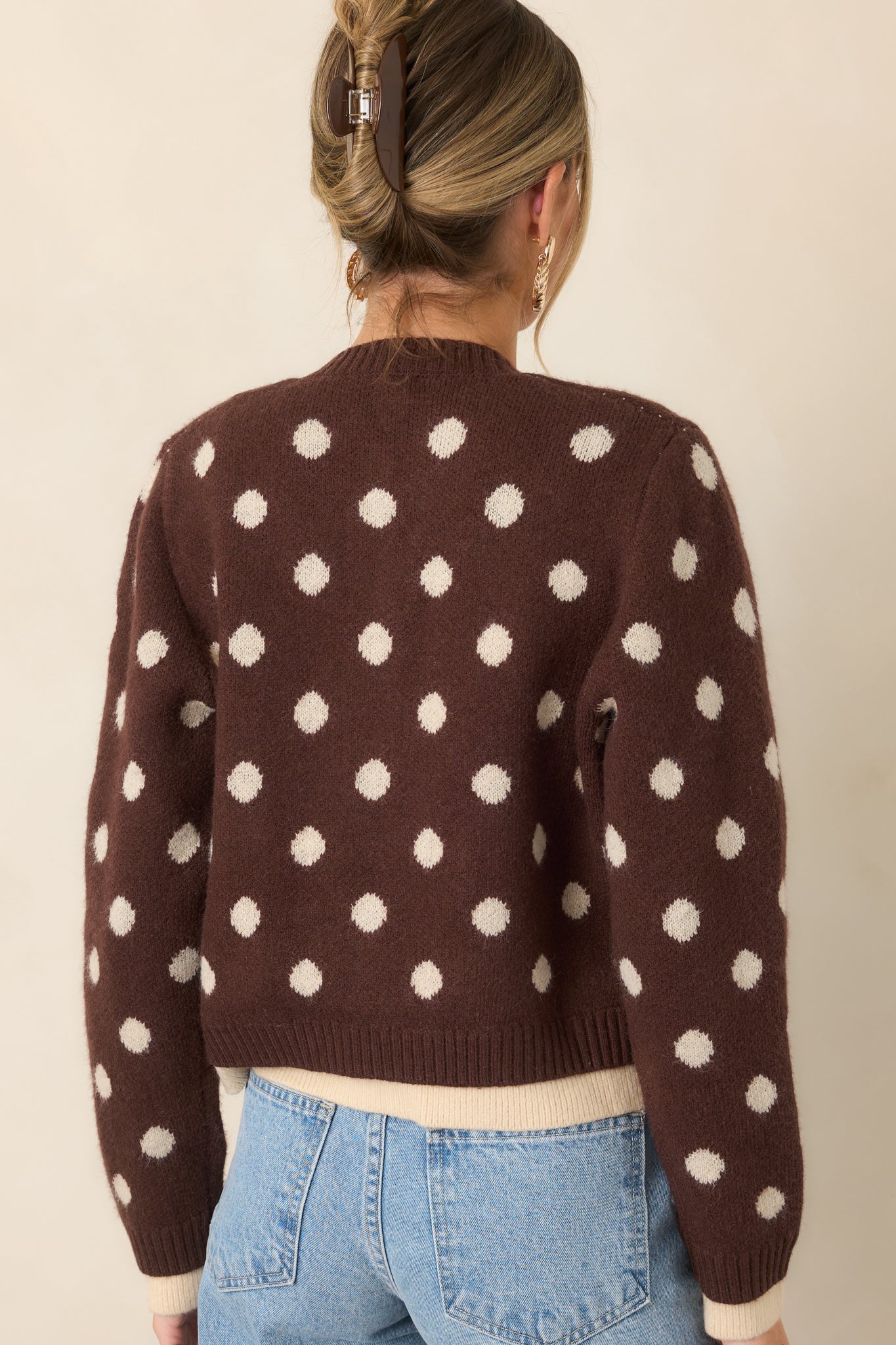 Rear view of the brown knit cardigan featuring an allover ivory polka dot pattern and ribbed hem with contrasting ivory trim.