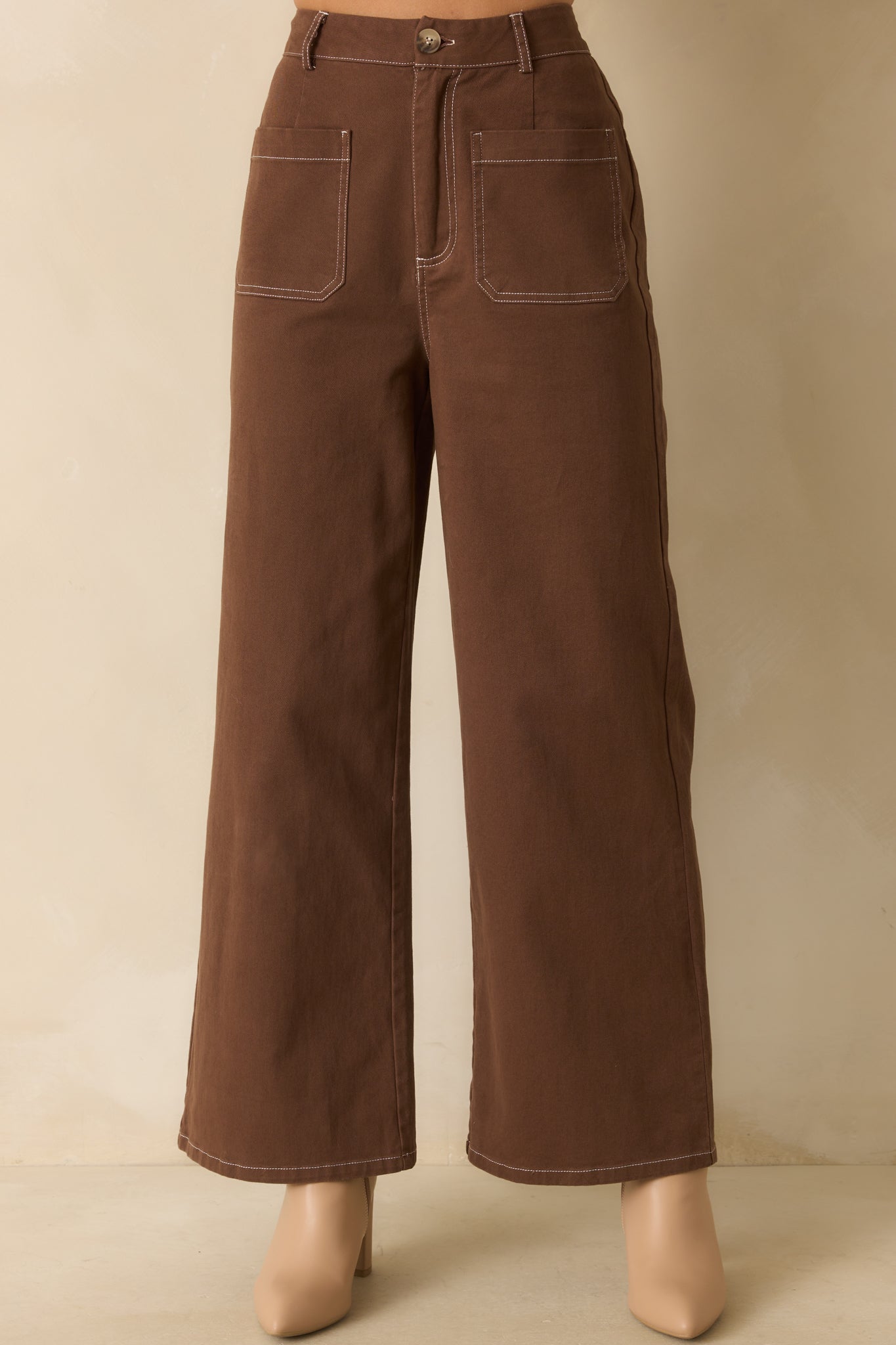 Detailed view of brown cotton fabric showing ivory topstitching, pocket construction, and seam detail.