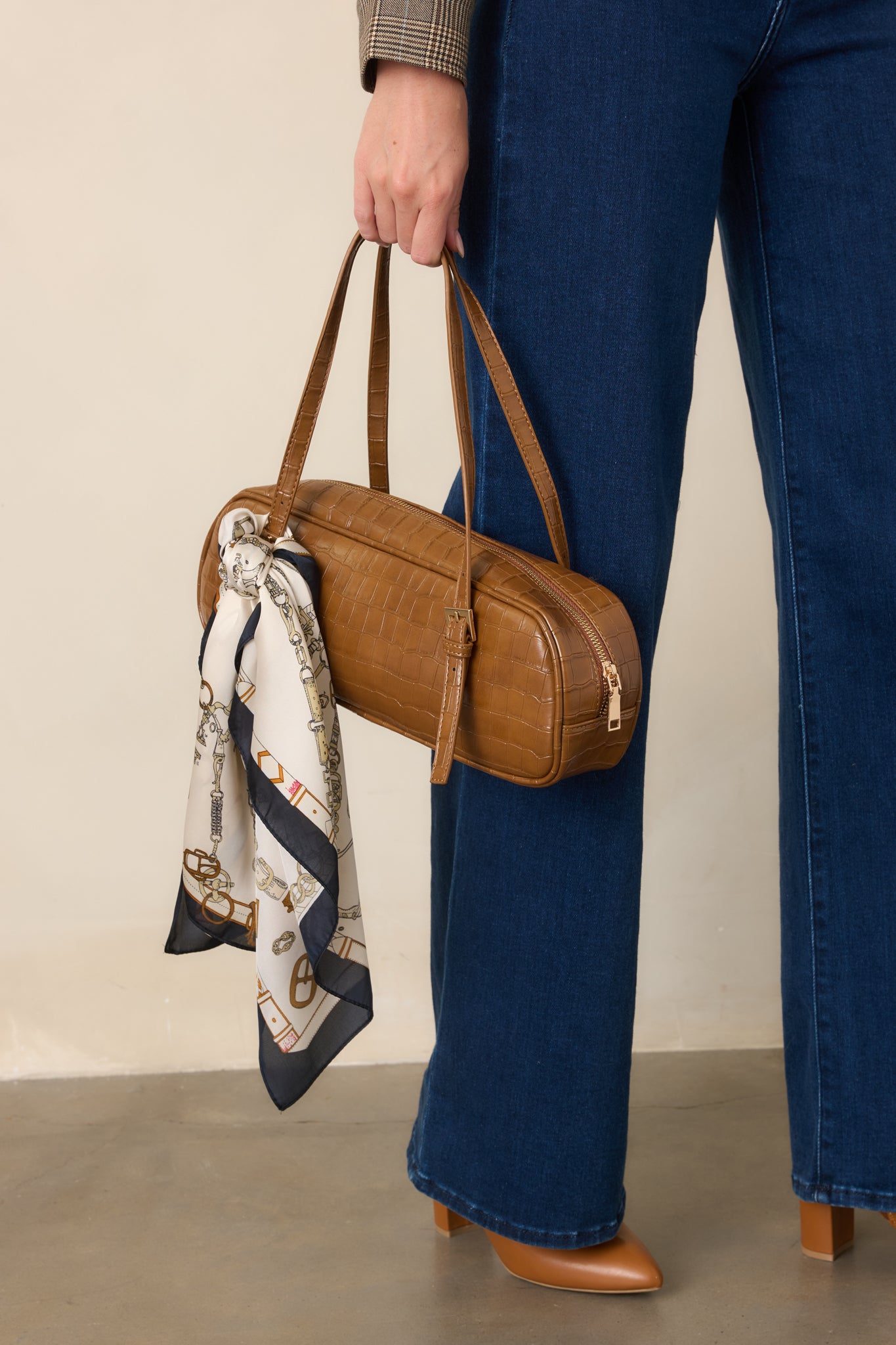 Close view of the brown handbag highlighting its raised croc-embossed texture, structured top handles, and refined silhouette.