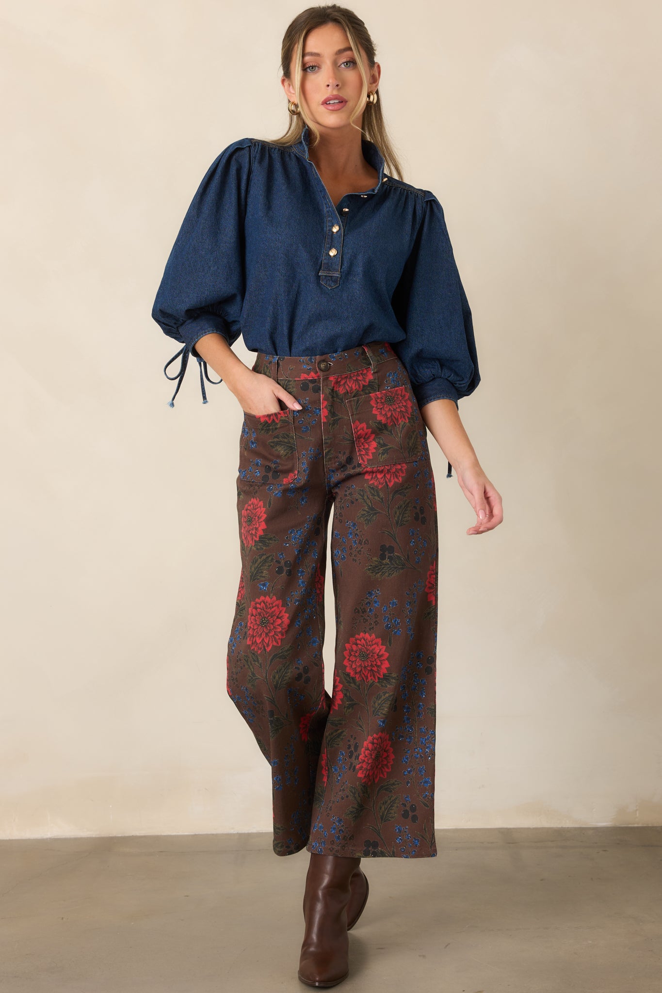 Brown cropped wide-leg pants covered in red floral blooms, cobalt accents, olive greenery, and subtle black details.