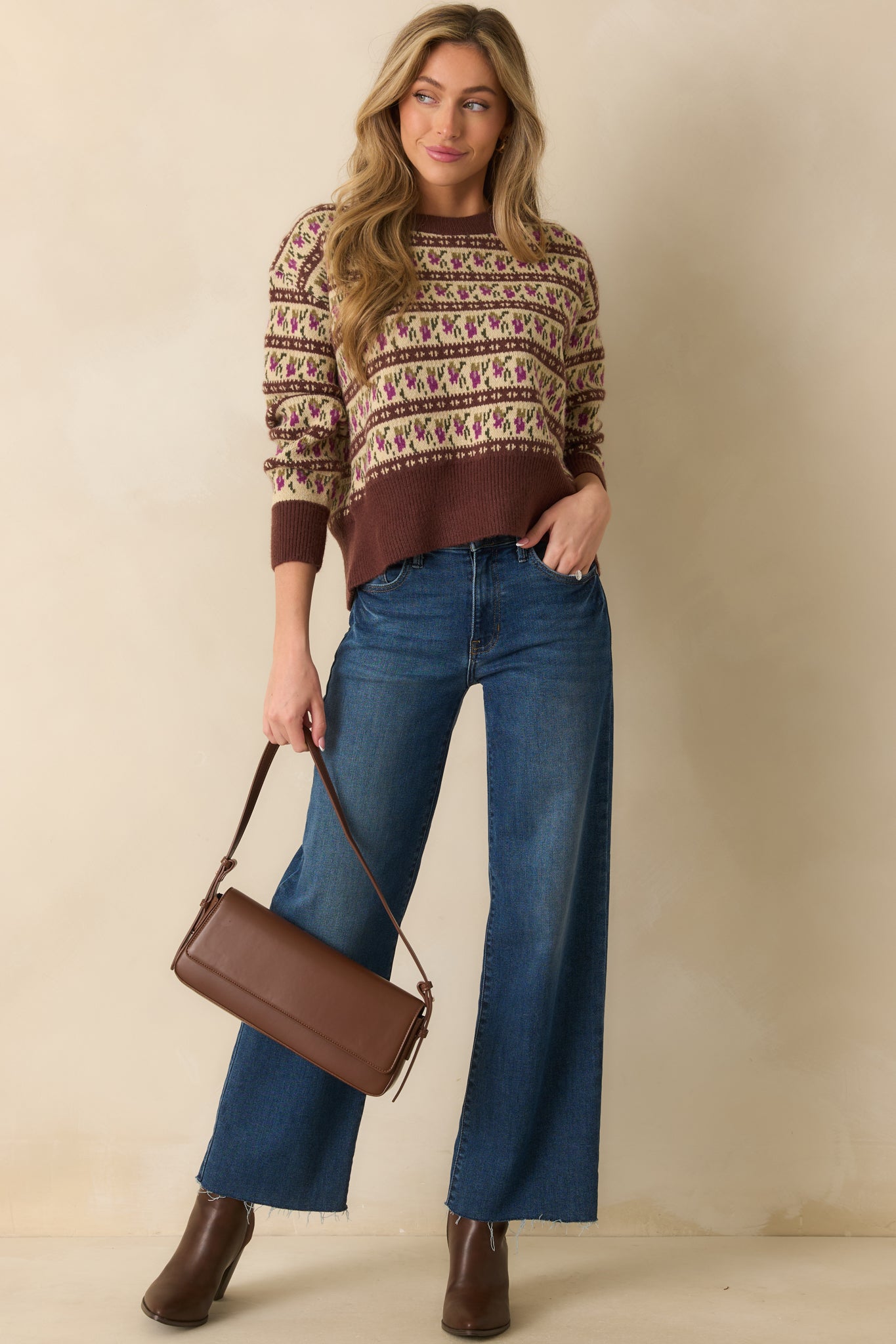 Brown sweater with crew neckline and long sleeves, featuring a relaxed fit and allover ivory, purple, and green Fair Isle pattern.