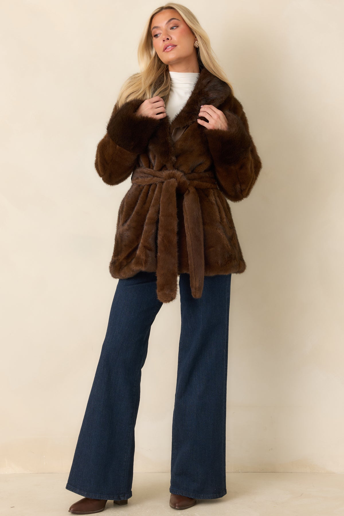 Brown faux fur coat with a matching waist tie and wide lapels framing the open front.