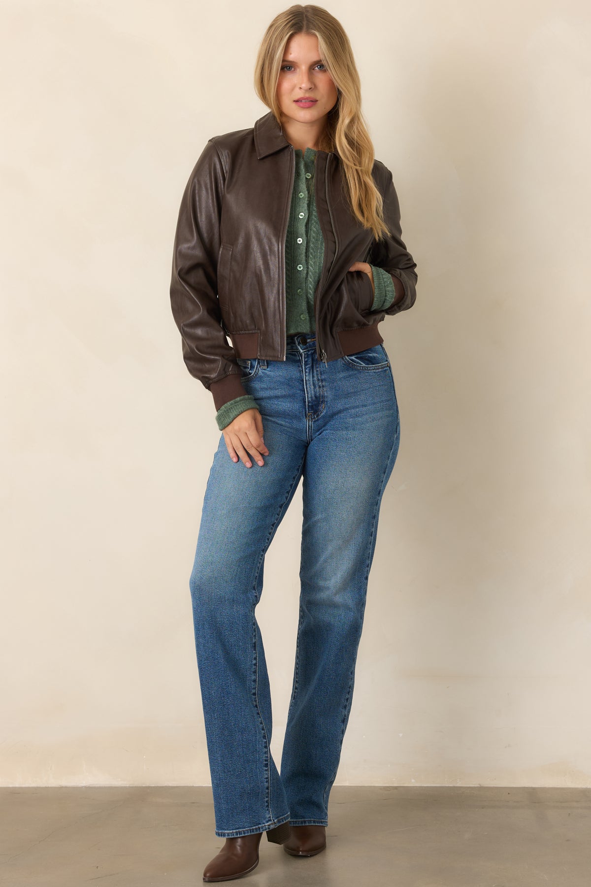Smooth brown faux leather jacket featuring a collared neckline, front zipper closure, welt pockets, and ribbed knit trim.