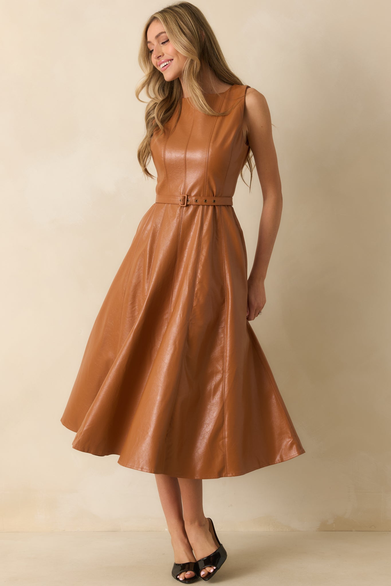 Brown faux leather midi dress styled with a sleeveless cut, belted waist, and smooth paneled texture.