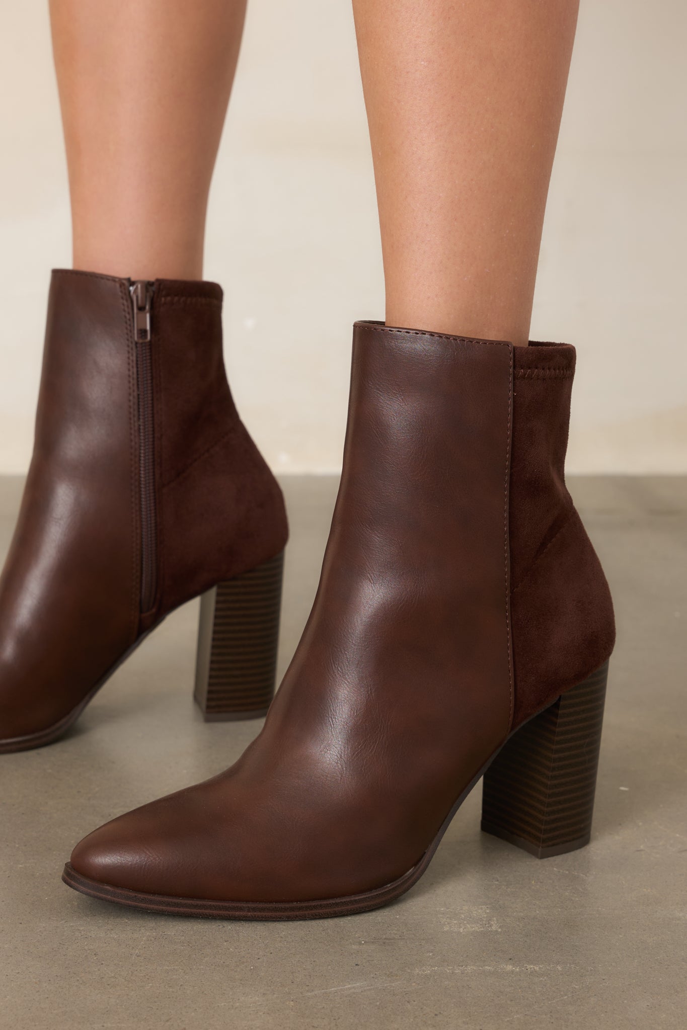 Close view of the brown boots highlighting the pointed toe and smooth faux leather finish across the front.