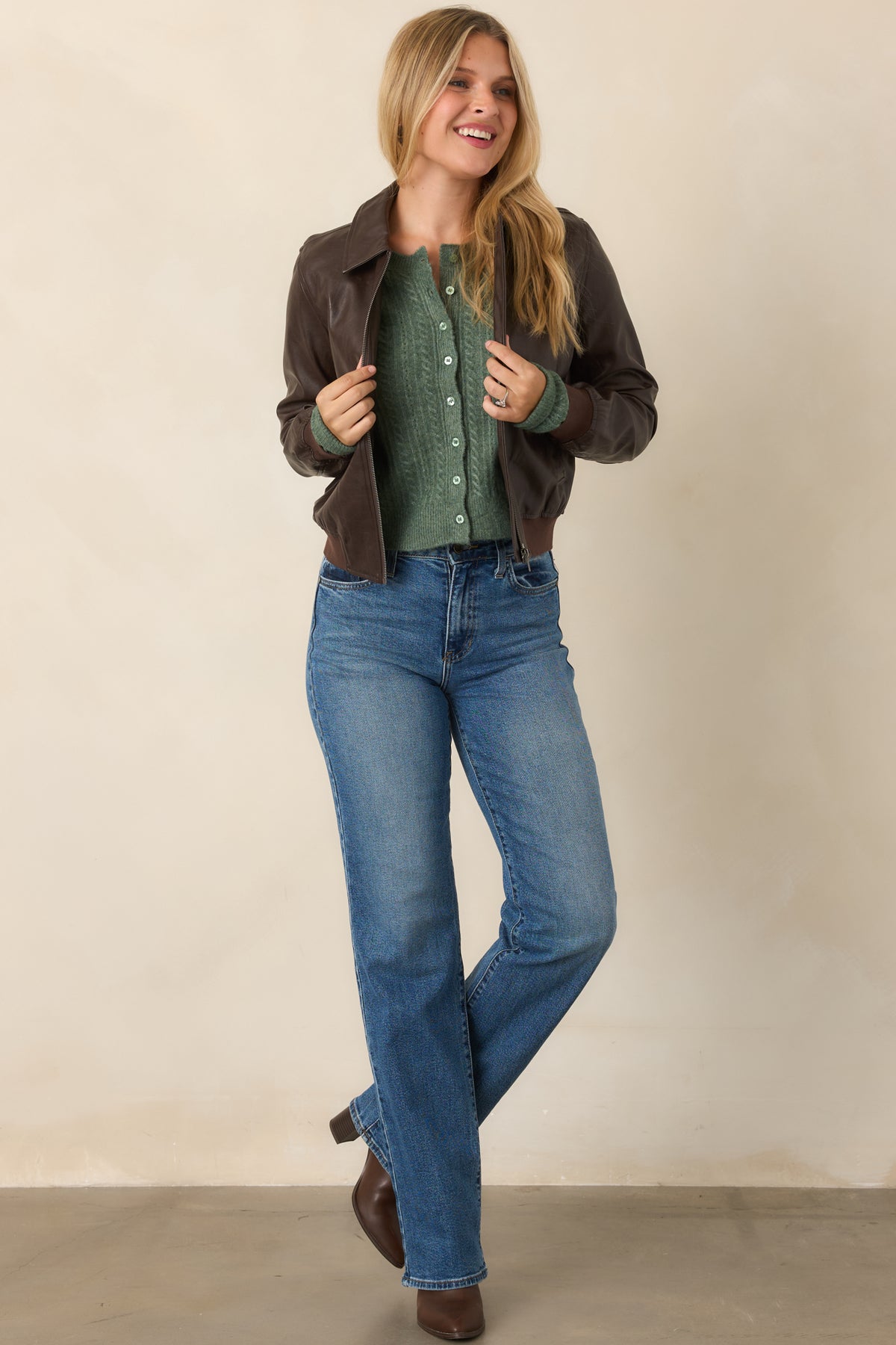 Streamlined brown faux leather bomber jacket featuring a front zipper, welt pockets, and softly gathered ribbed trim.