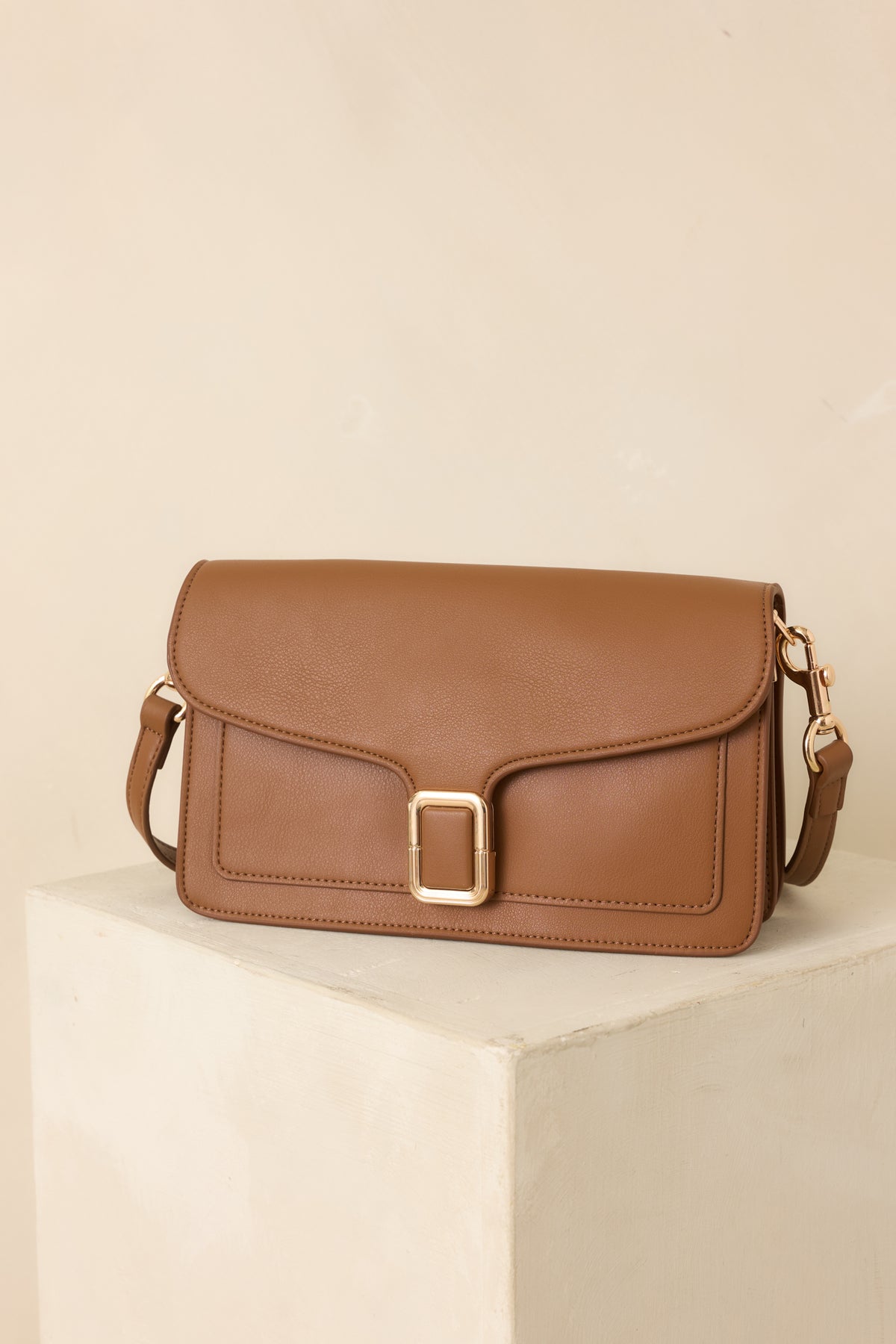 Brown faux leather handbag with a structured rectangular shape, envelope flap, and gold-tone buckle clasp.