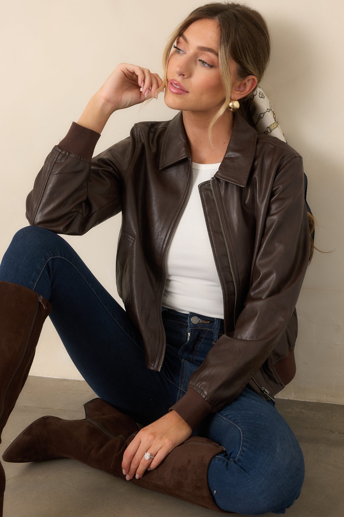 Brown faux leather jacket featuring a streamlined zip-front design, welt pockets, ribbed knit cuffs, and a gently gathered hem.